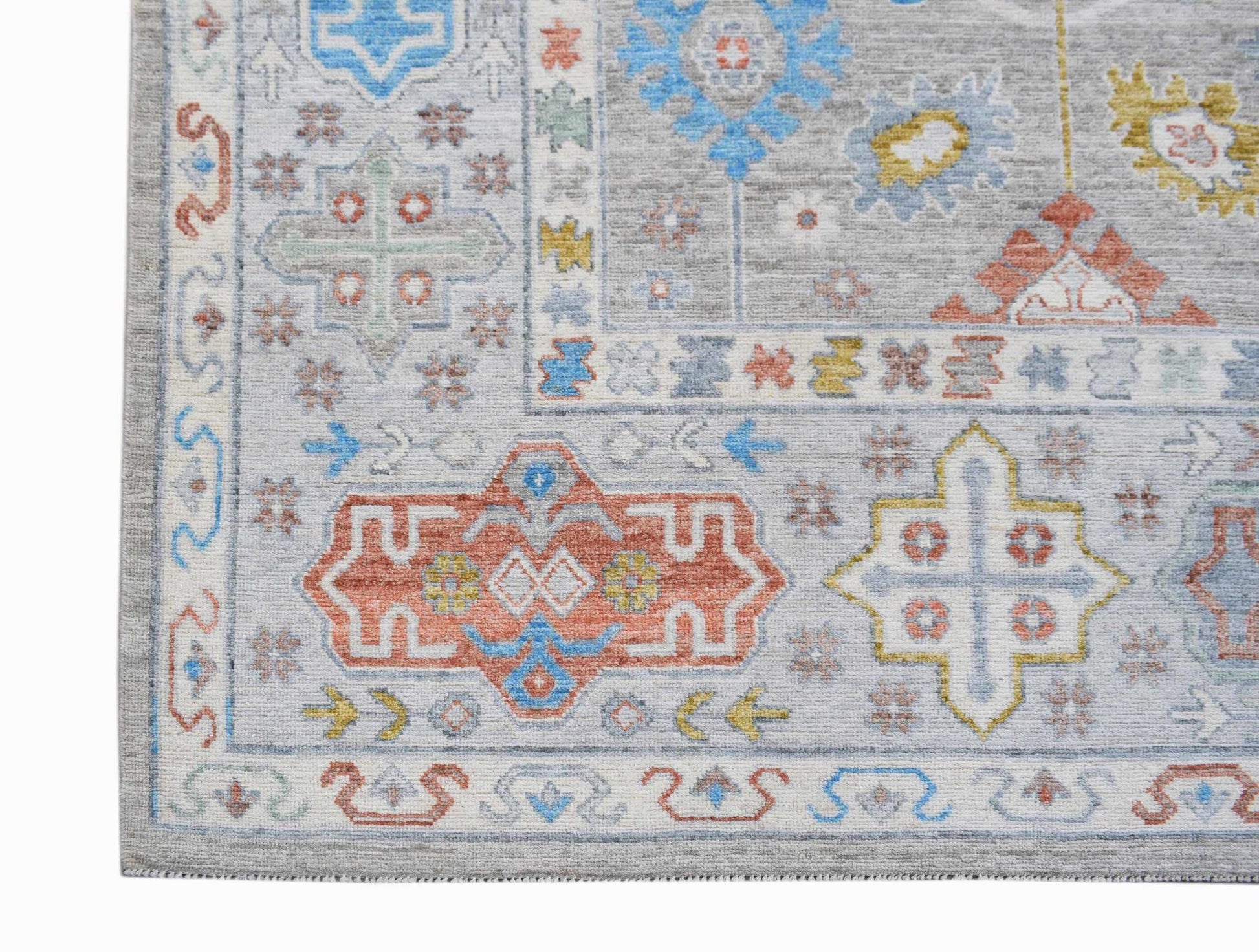 A handwoven Afghan Chobi rug featuring a light grey field with colorful geometric patterns.