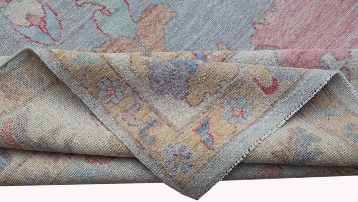A handwoven transitional Oushak rug featuring a floral pattern in soft pastel tones.