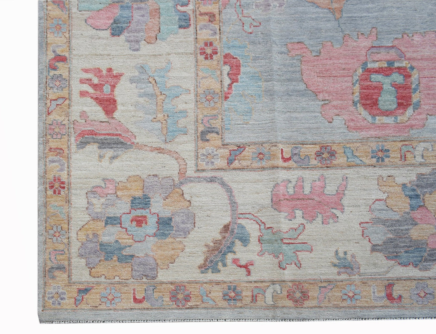 A handwoven transitional Oushak rug featuring floral motifs in soft pastel tones on a light field.