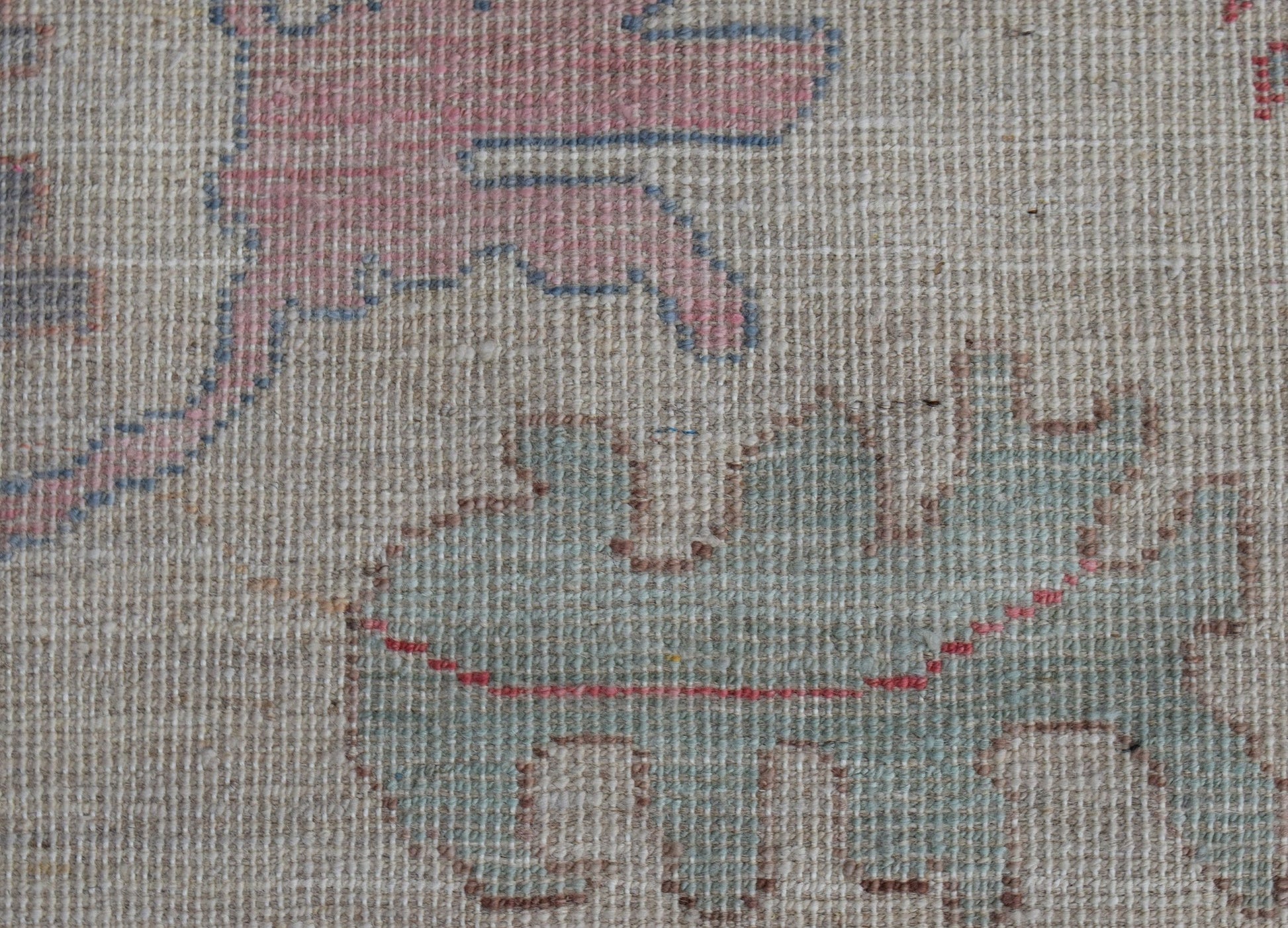 A close-up view of a handwoven wool rug featuring stylized pomegranate motifs in soft tones.