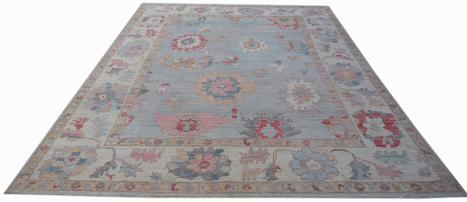 A handmade transitional Oushak rug featuring a light blue field with colorful floral motifs.