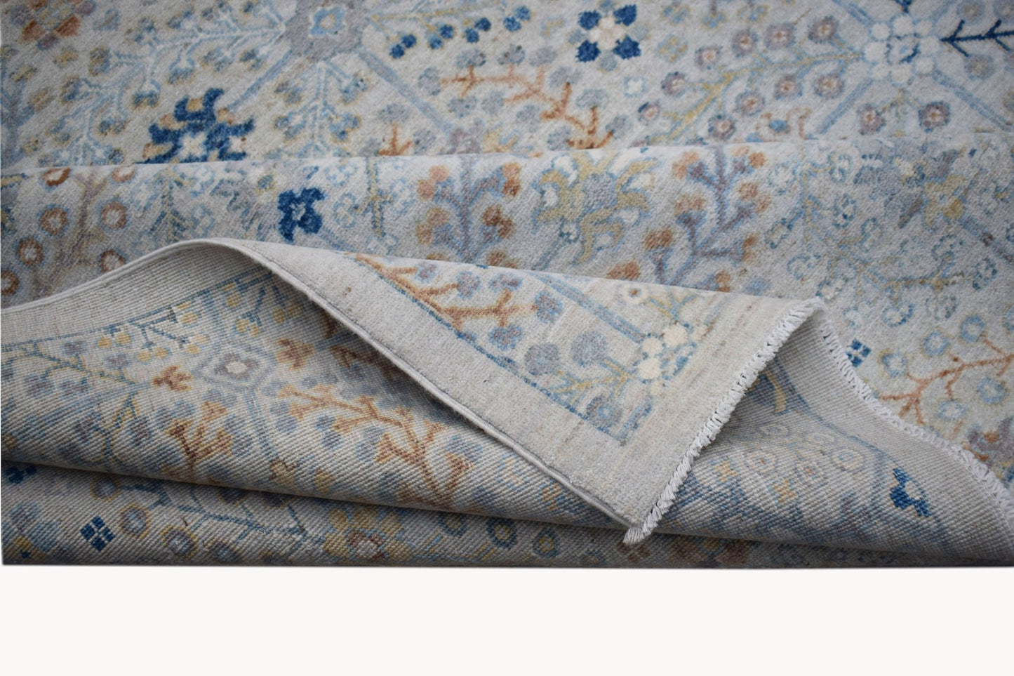 A handwoven Afghan Balkh rug featuring a traditional floral pattern in soft blue and tan tones.