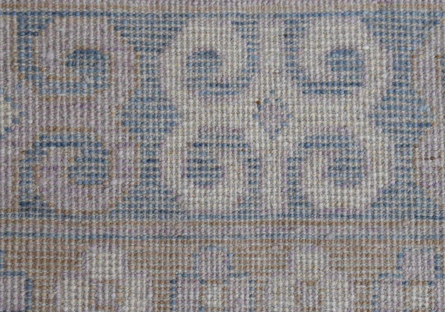 A close-up of a handwoven Afghan Chobi rug featuring blue pomegranate motifs on a beige wool base.