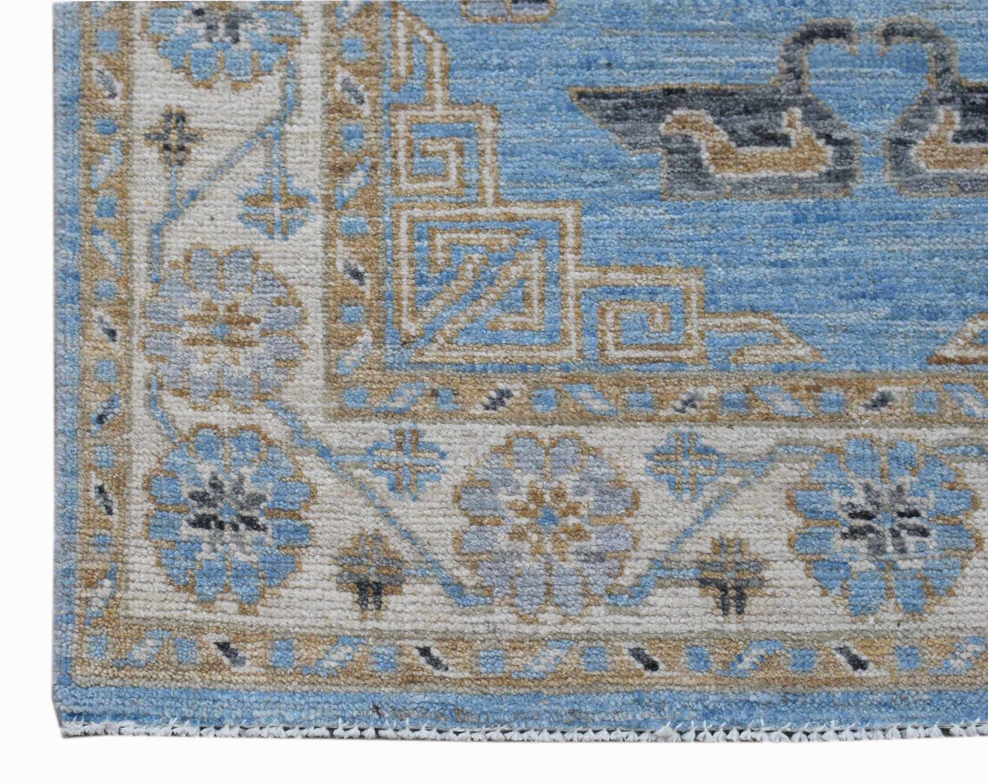 A corner view of a handwoven Afghan Chobi runner featuring blue and tan floral and geometric motifs.