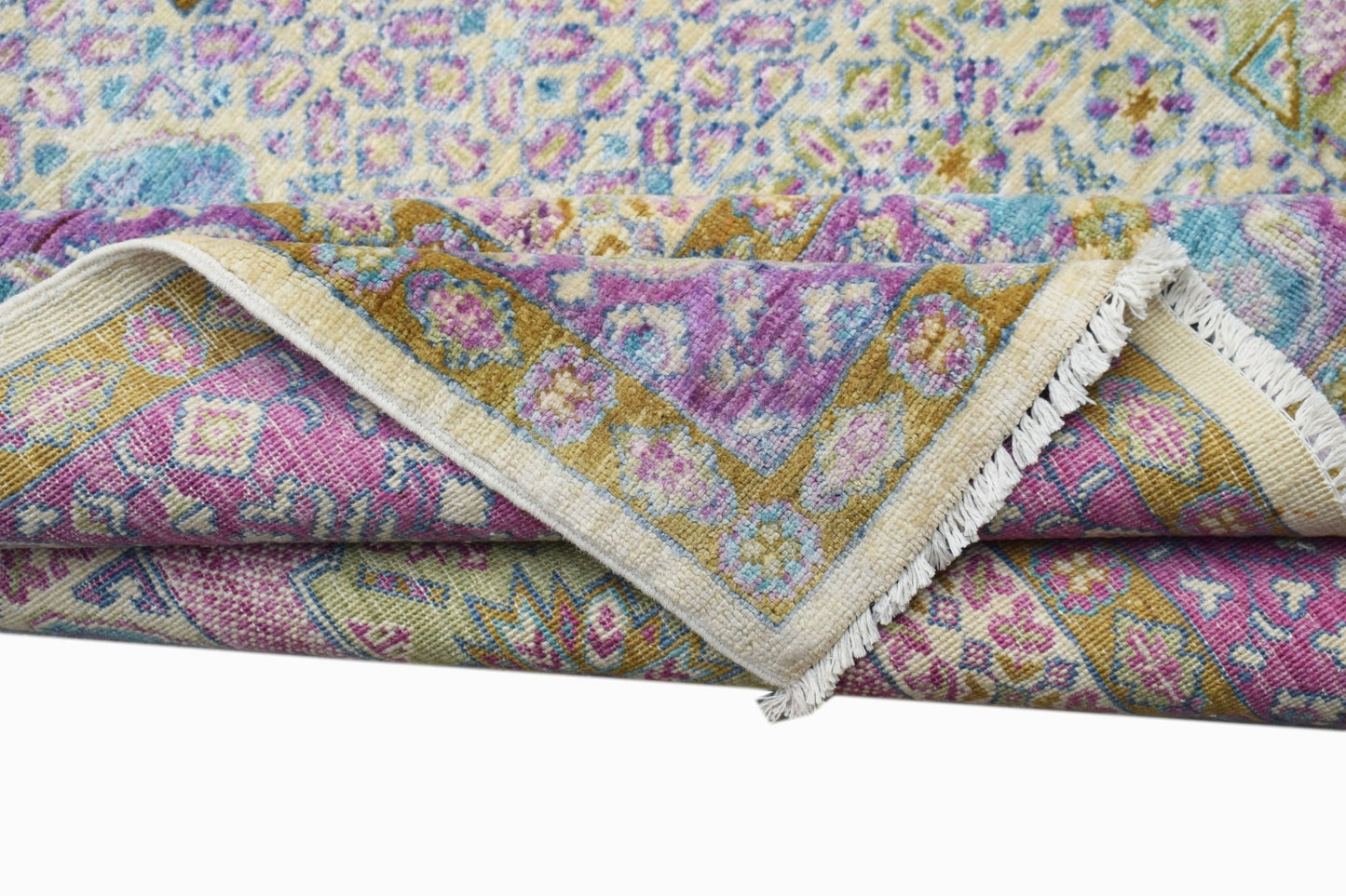 A folded Afghan Balkh rug featuring a traditional floral pattern in shades of purple, blue, and gold.