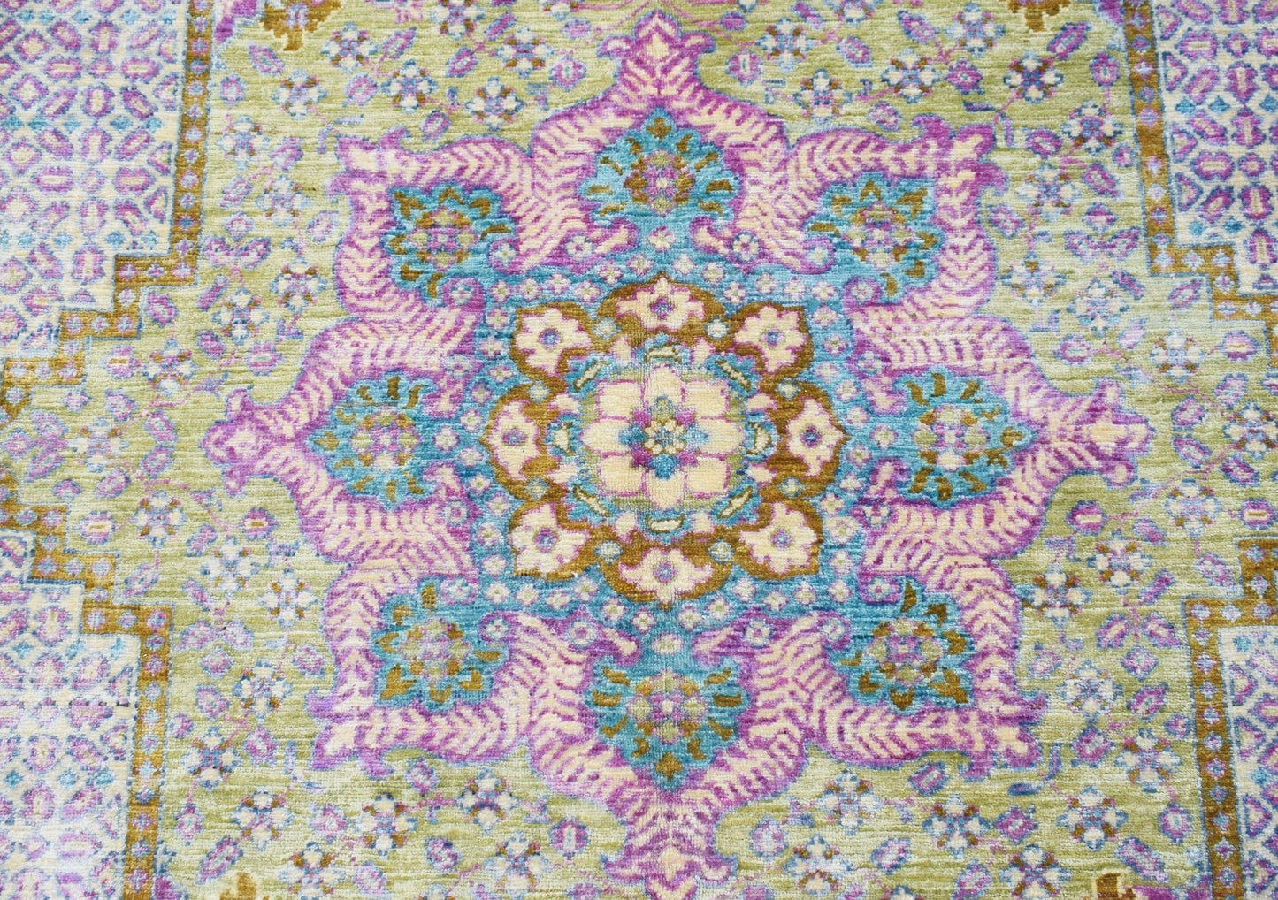 An Afghan Balkh rug featuring a central floral medallion in shades of purple, blue, and gold.
