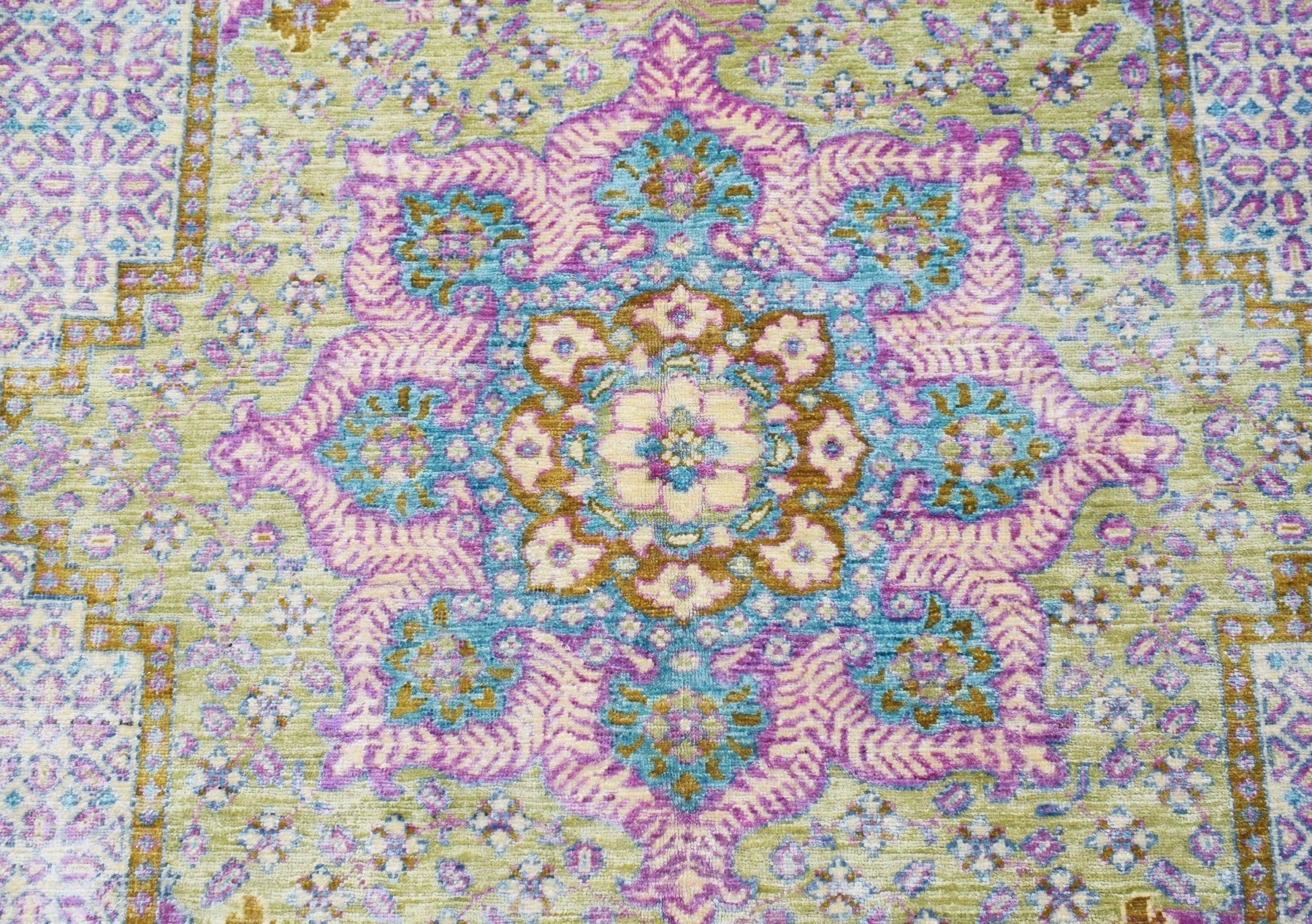 An Afghan Balkh rug featuring a central floral medallion in shades of purple, blue, and gold.