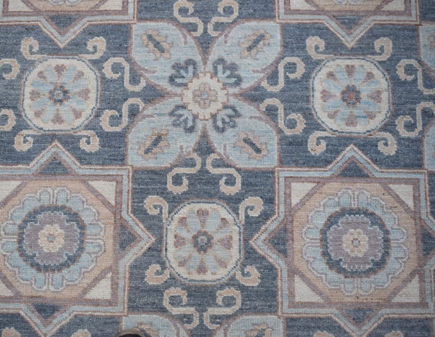 Handwoven Afghan Chobi rug featuring a traditional geometric floral pattern in blue and beige tones.