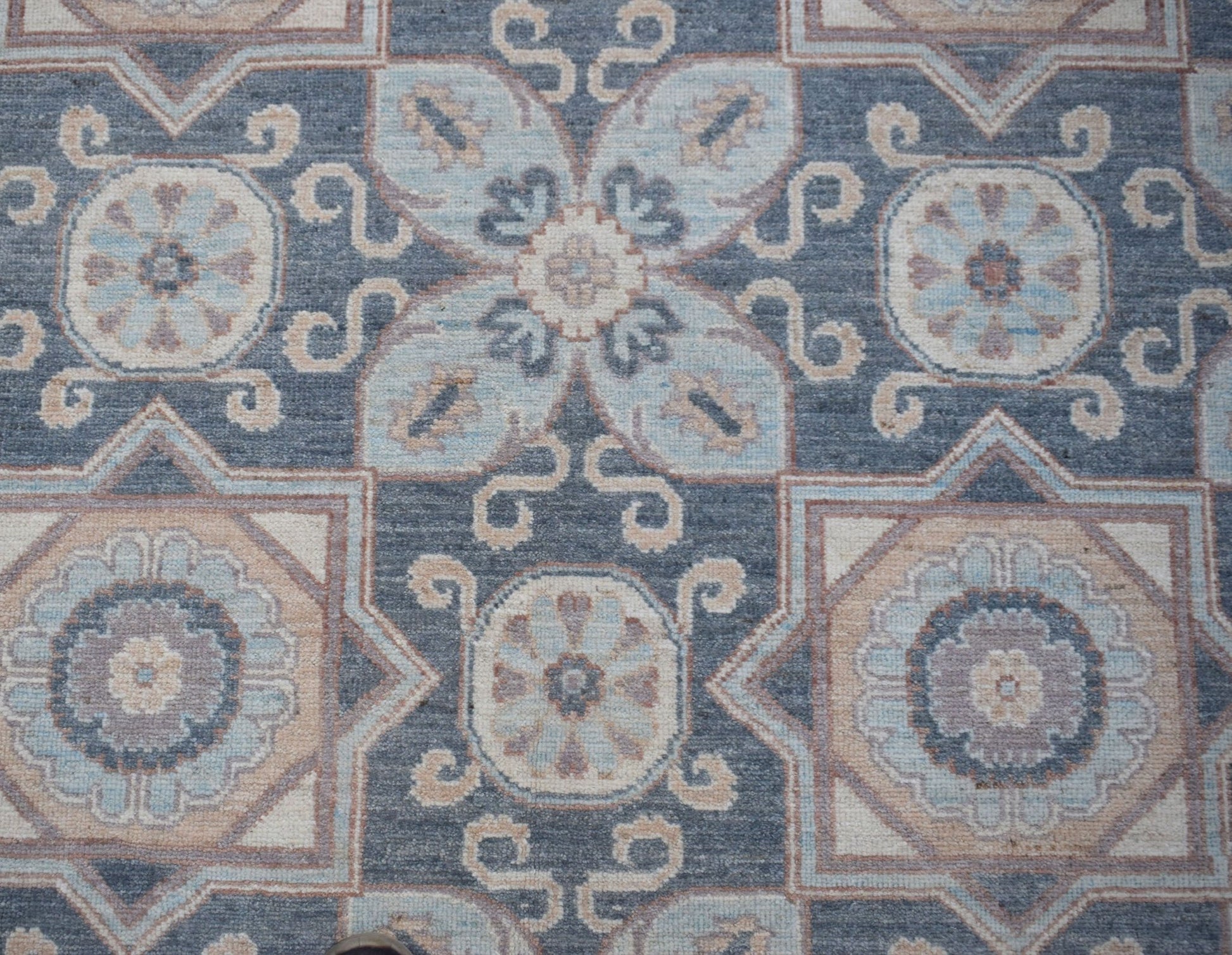 Handwoven Afghan Chobi rug featuring a traditional geometric floral pattern in blue and beige tones.
