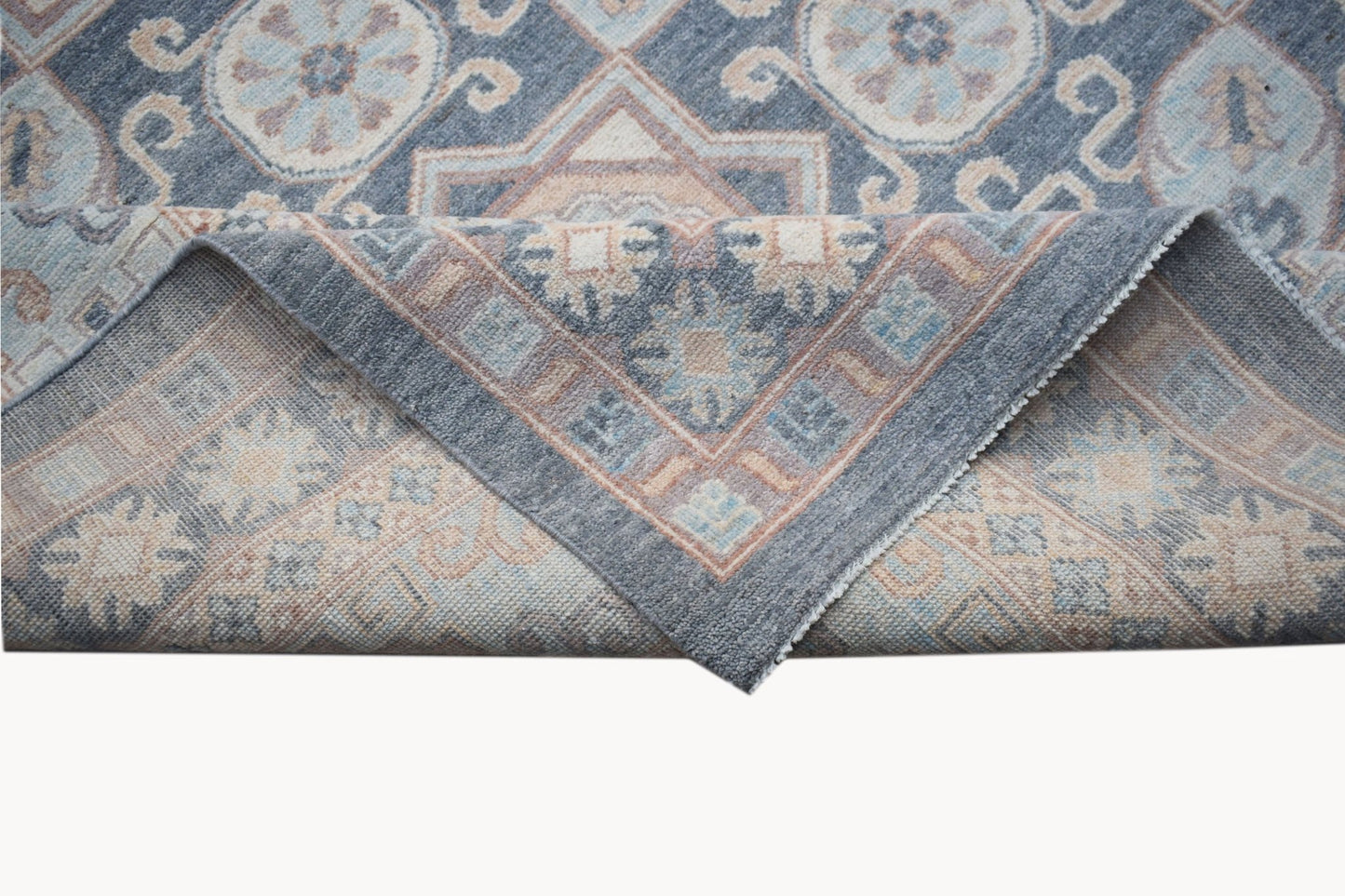 A handwoven Afghan Chobi rug featuring a traditional geometric pattern in muted blue and beige tones.
