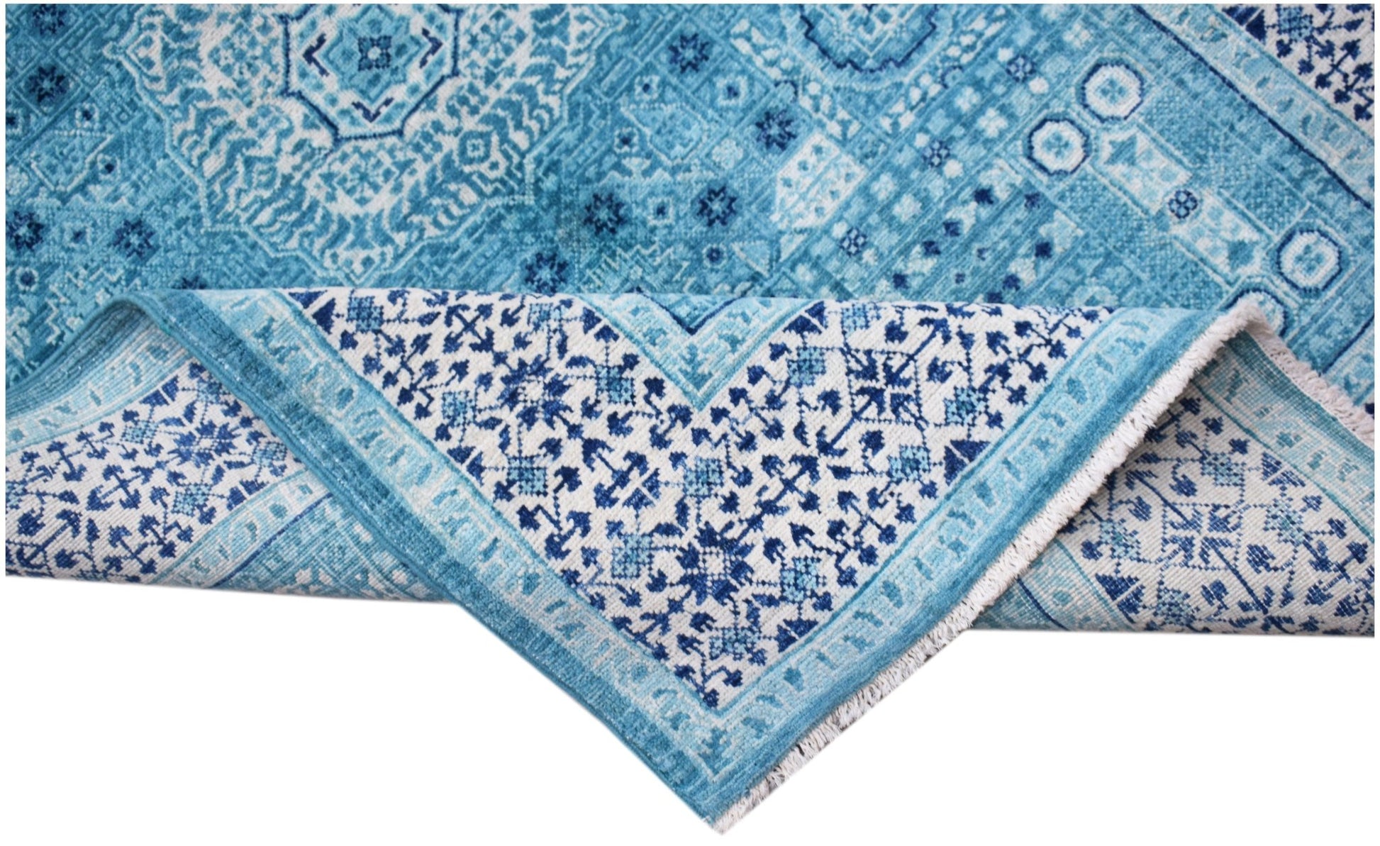 A handwoven Afghan Chobi rug featuring a blue Mamluk pattern with a folded corner.