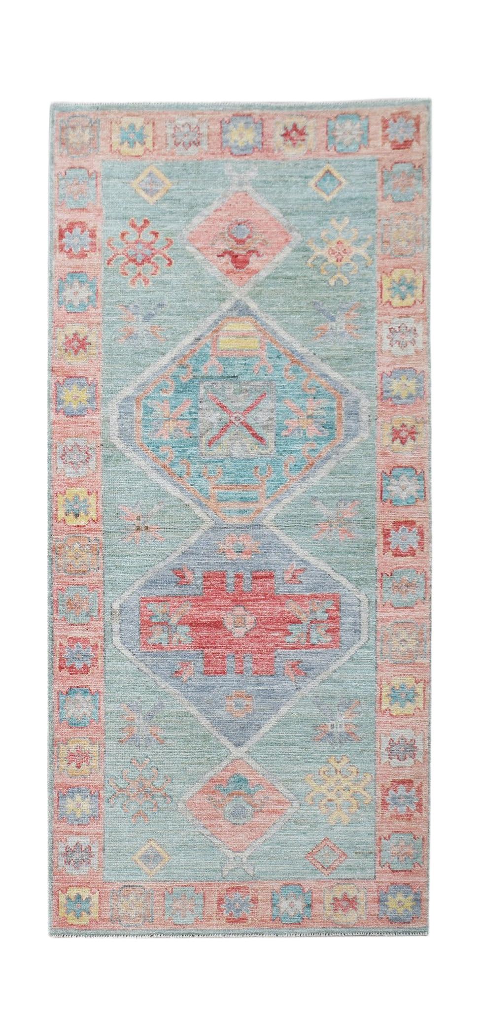 A handwoven wool runner rug featuring a transitional Oushak pattern in soft blue and pink tones.