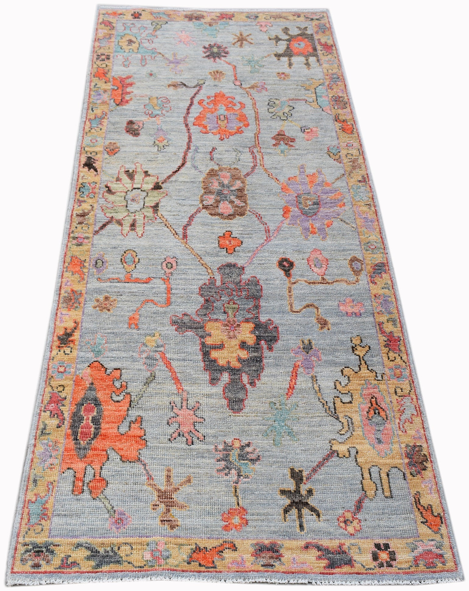 A handwoven transitional Oushak runner featuring a floral pattern in vibrant colors on a blue base.