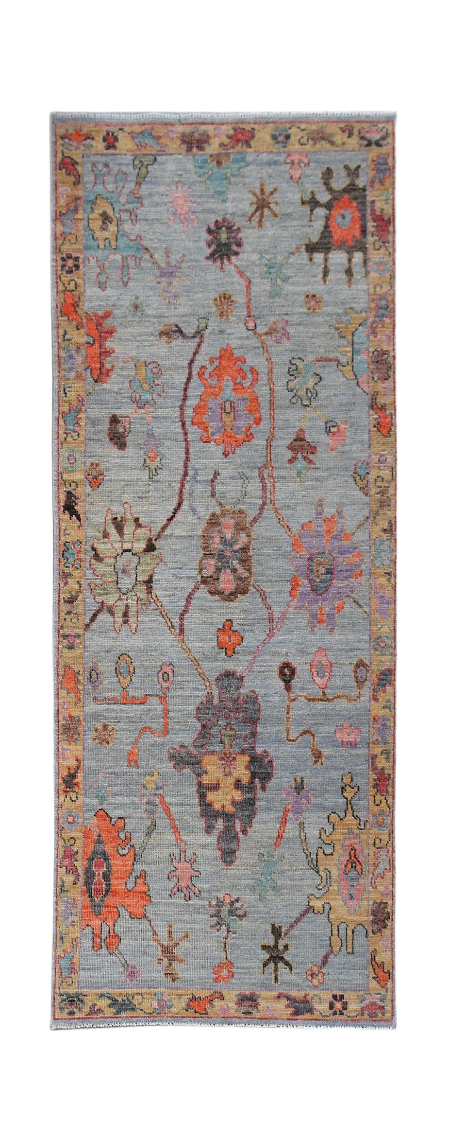 A handwoven wool runner rug featuring a transitional floral pattern in vibrant colors on a blue base.