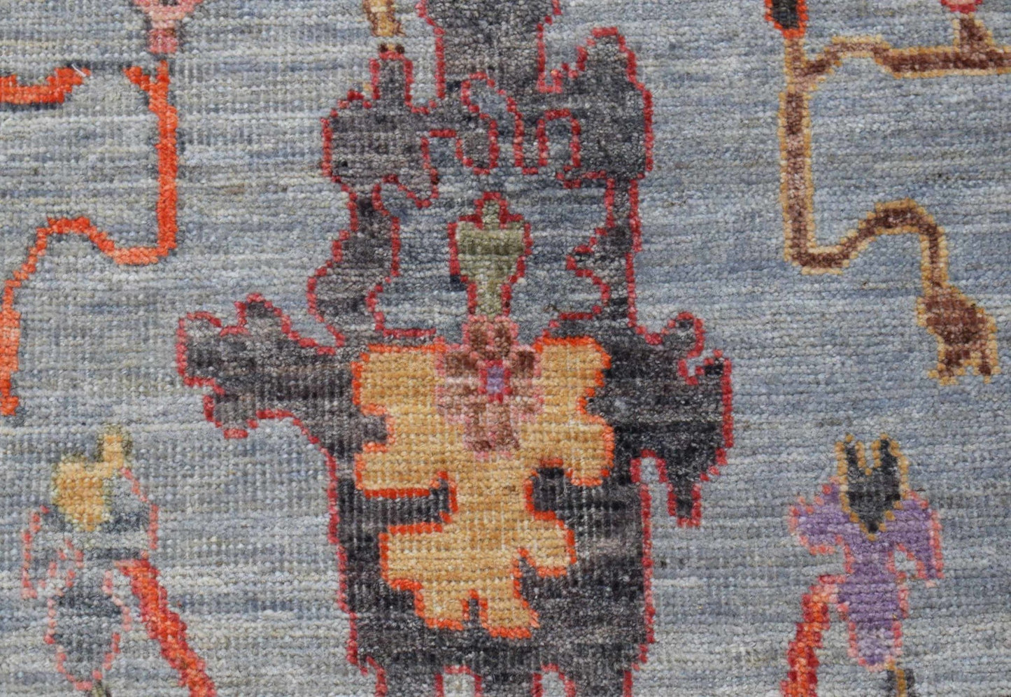 A handwoven wool runner featuring a transitional Oushak pattern in blue, orange, and grey tones.