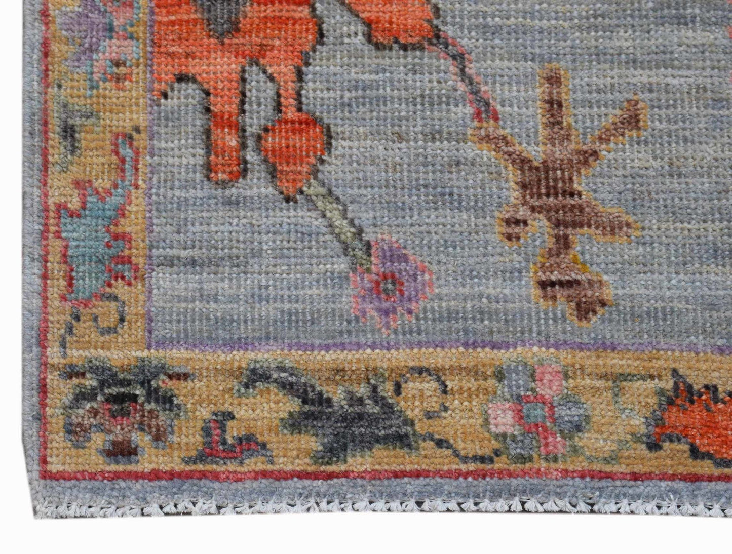 A handwoven transitional Oushak runner featuring a floral pattern on a blue field with a tan border.