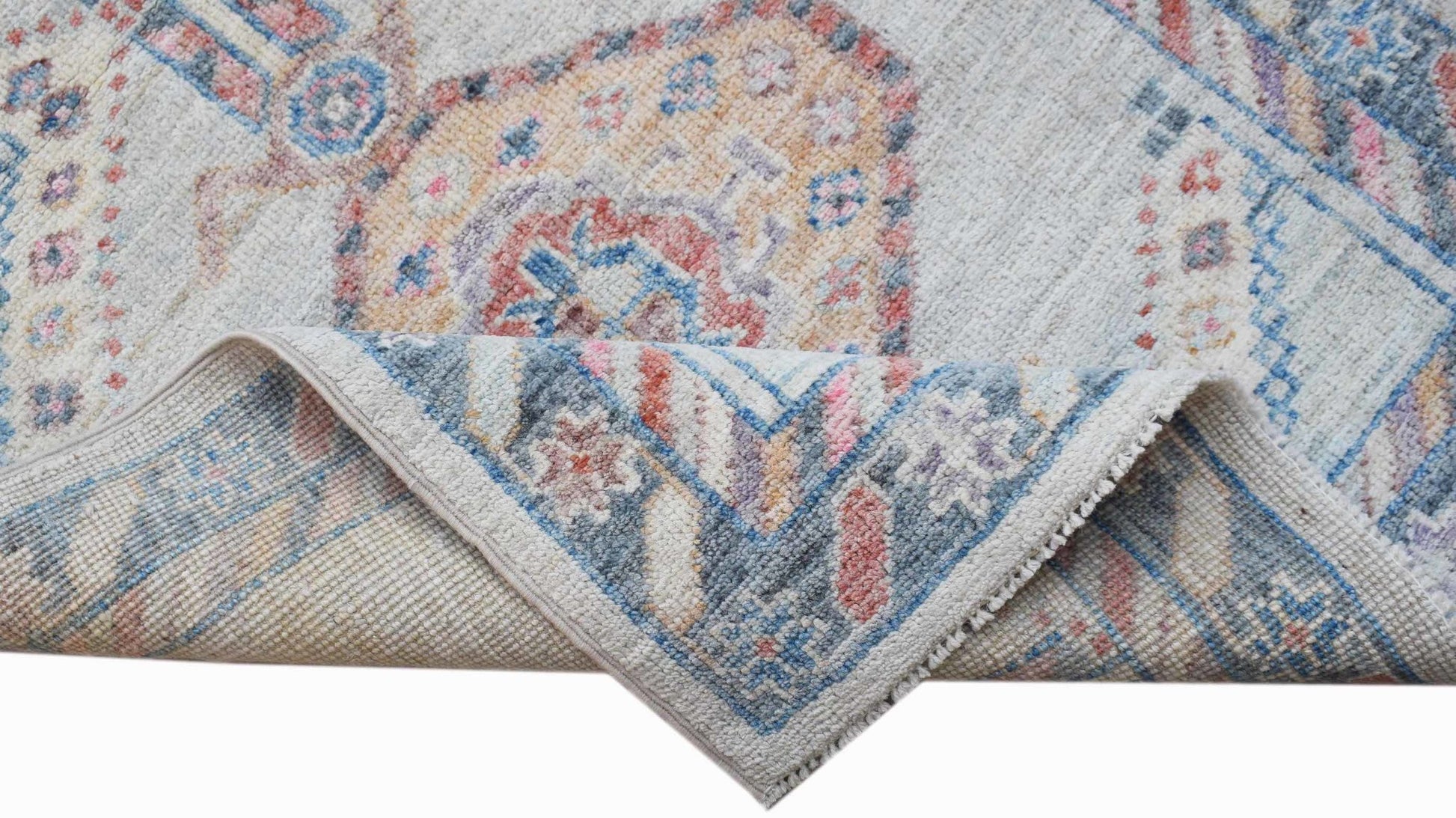 A handwoven transitional Oushak runner featuring a floral pattern in blue, pink, and beige tones.