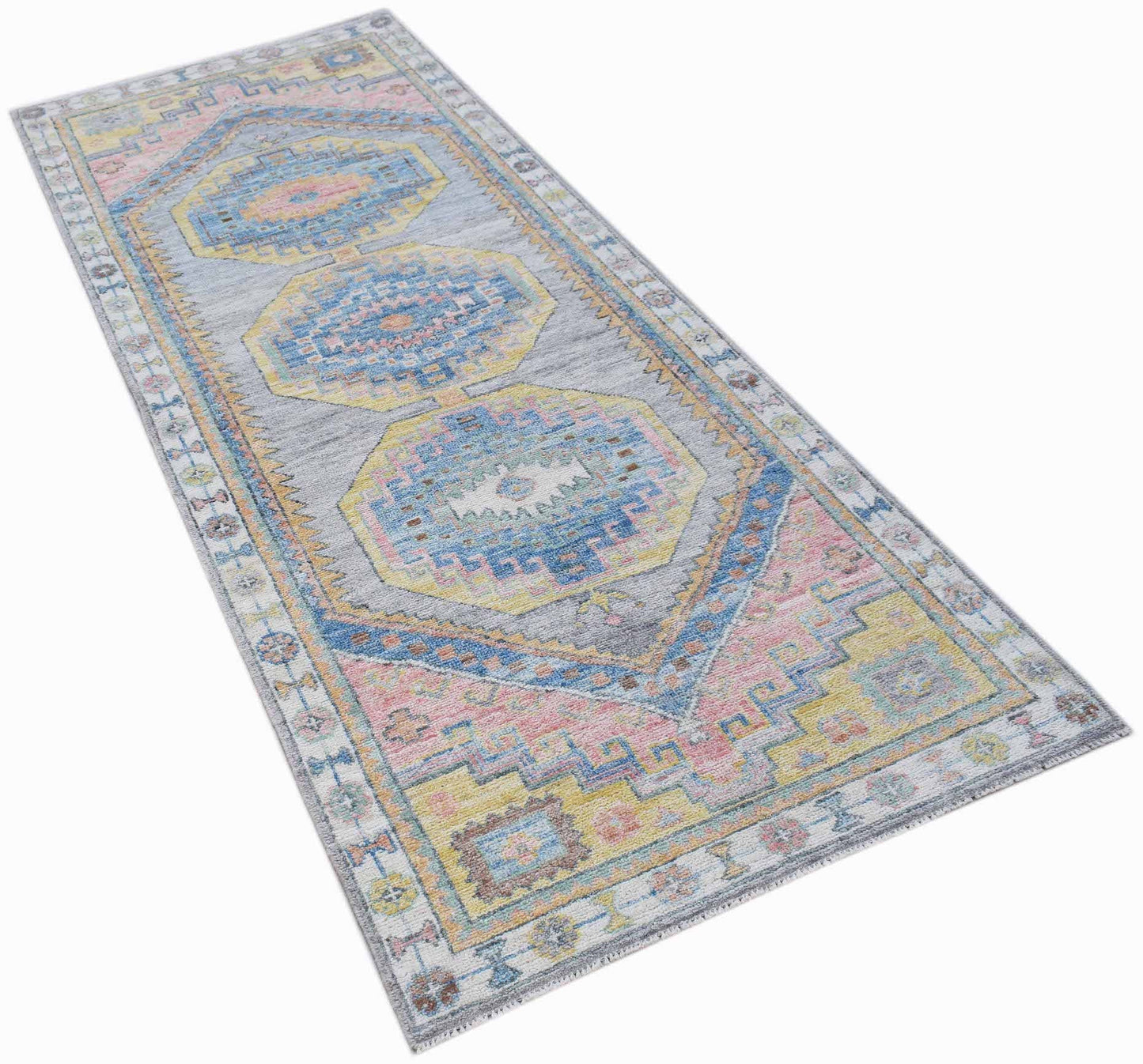 A handwoven wool runner rug featuring a transitional Oushak pattern in soft pastel colors.