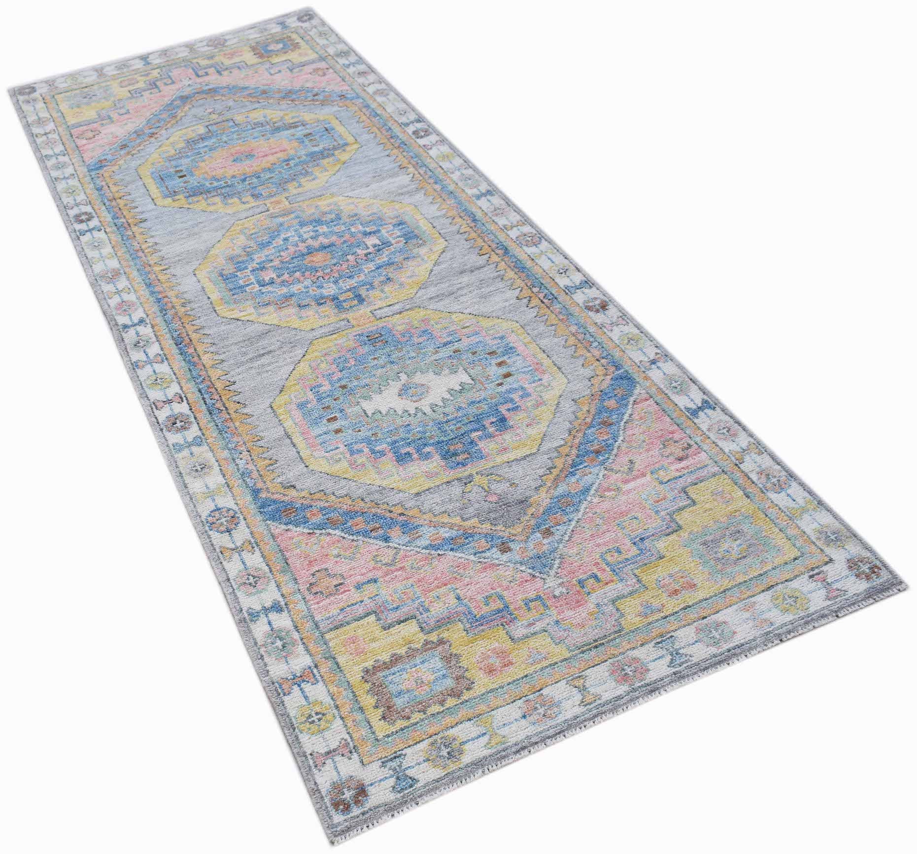 A handwoven wool runner rug featuring a transitional Oushak pattern in soft pastel colors.