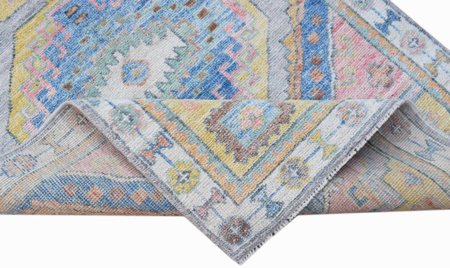 A handwoven wool runner rug featuring a traditional Oushak pattern in soft blue, pink, and yellow.