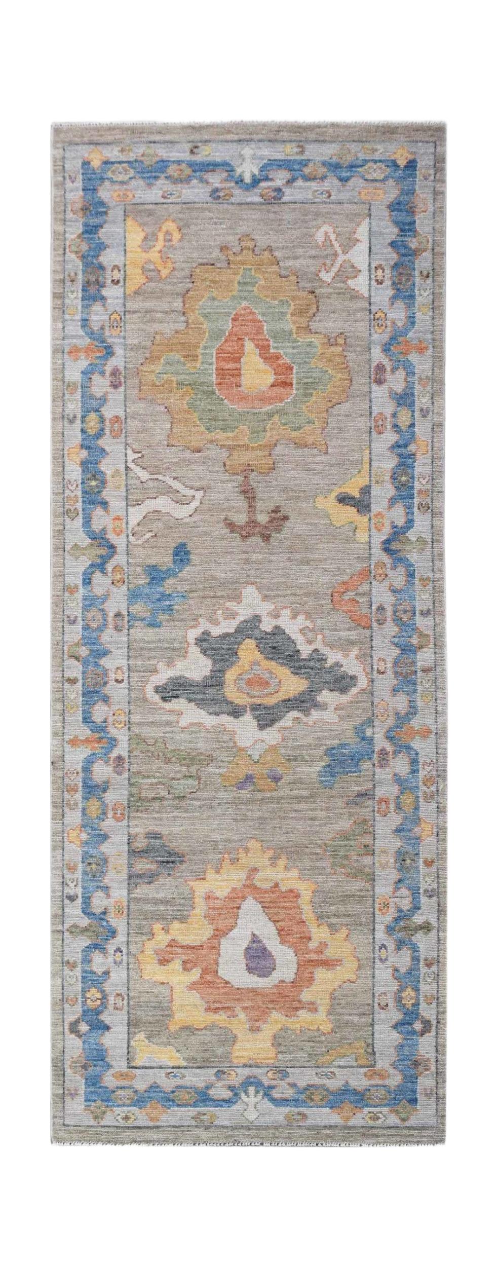 A handwoven wool runner rug featuring a transitional Oushak floral pattern in muted colors.