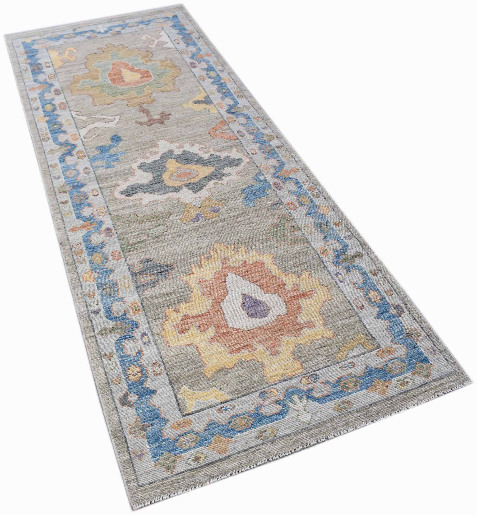 A handwoven transitional Oushak runner rug featuring a floral pattern in blue, yellow, and orange.
