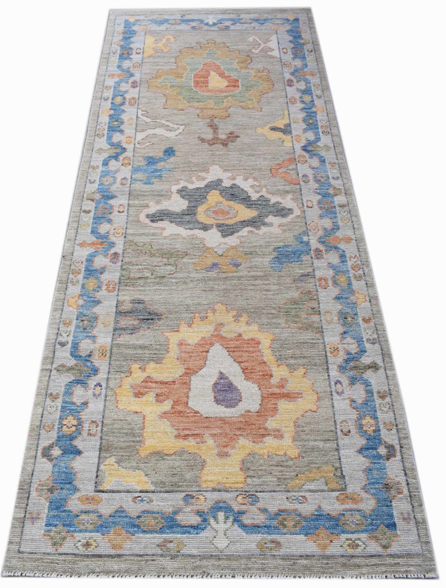 A handwoven transitional Oushak runner featuring a floral pattern in blue, orange, and yellow.