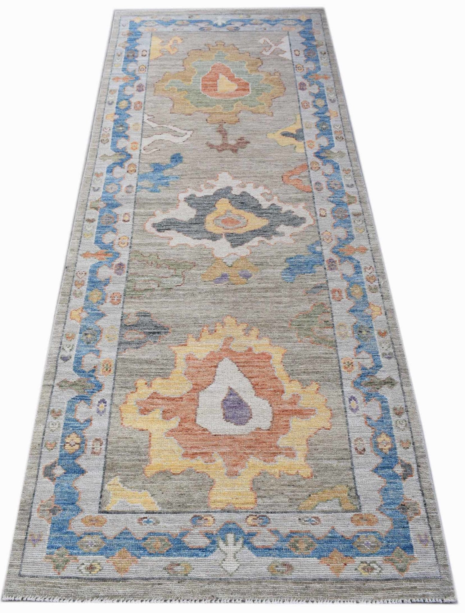 A handwoven transitional Oushak runner featuring a floral pattern in blue, orange, and yellow.