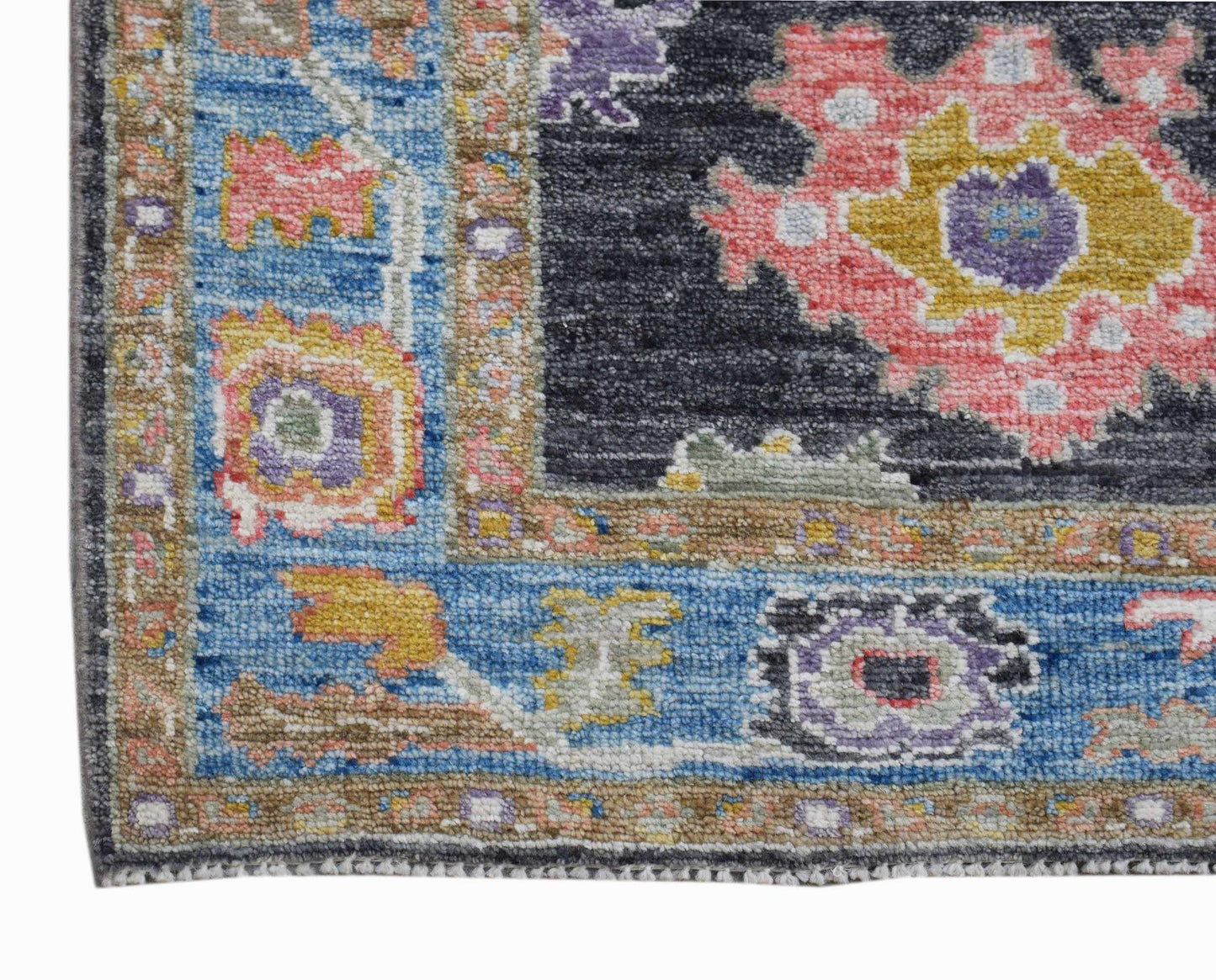 A handwoven wool runner featuring a floral Oushak pattern in blue, pink, and charcoal tones.
