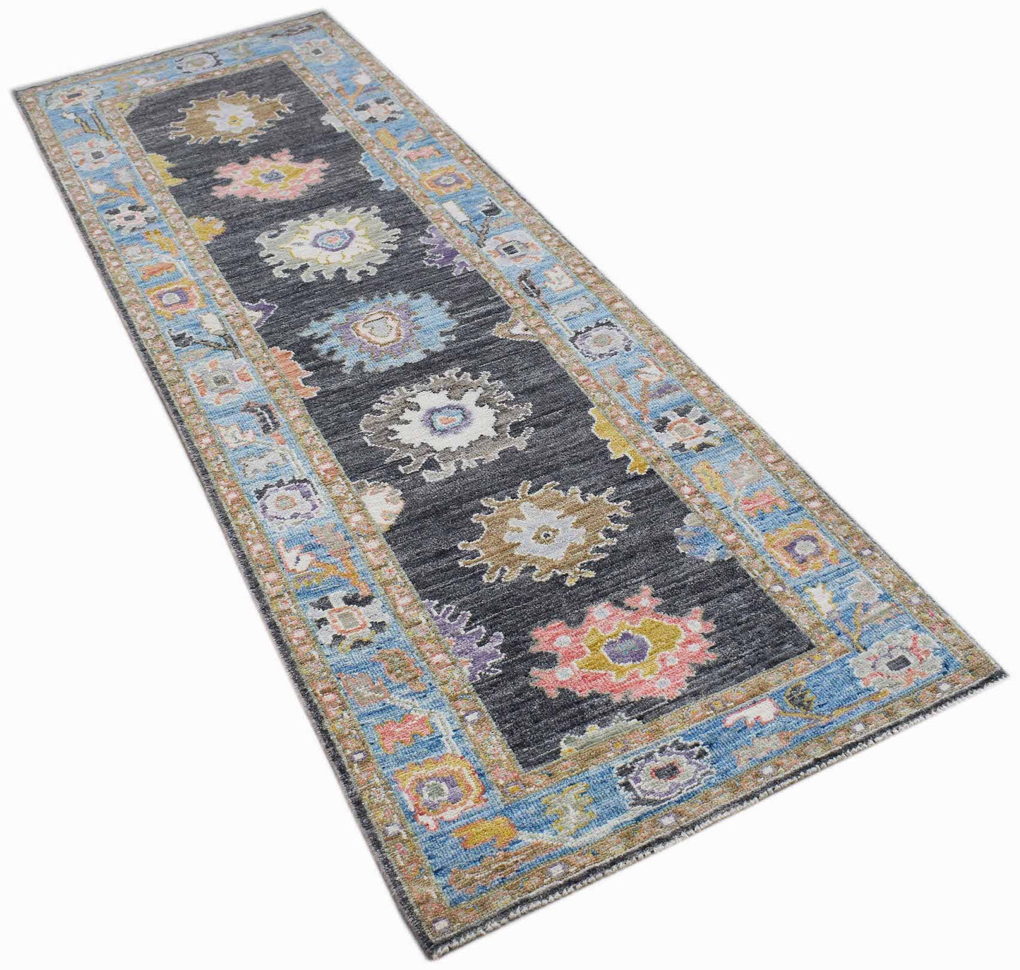 A handwoven wool runner rug featuring a dark grey center with colorful floral medallions.