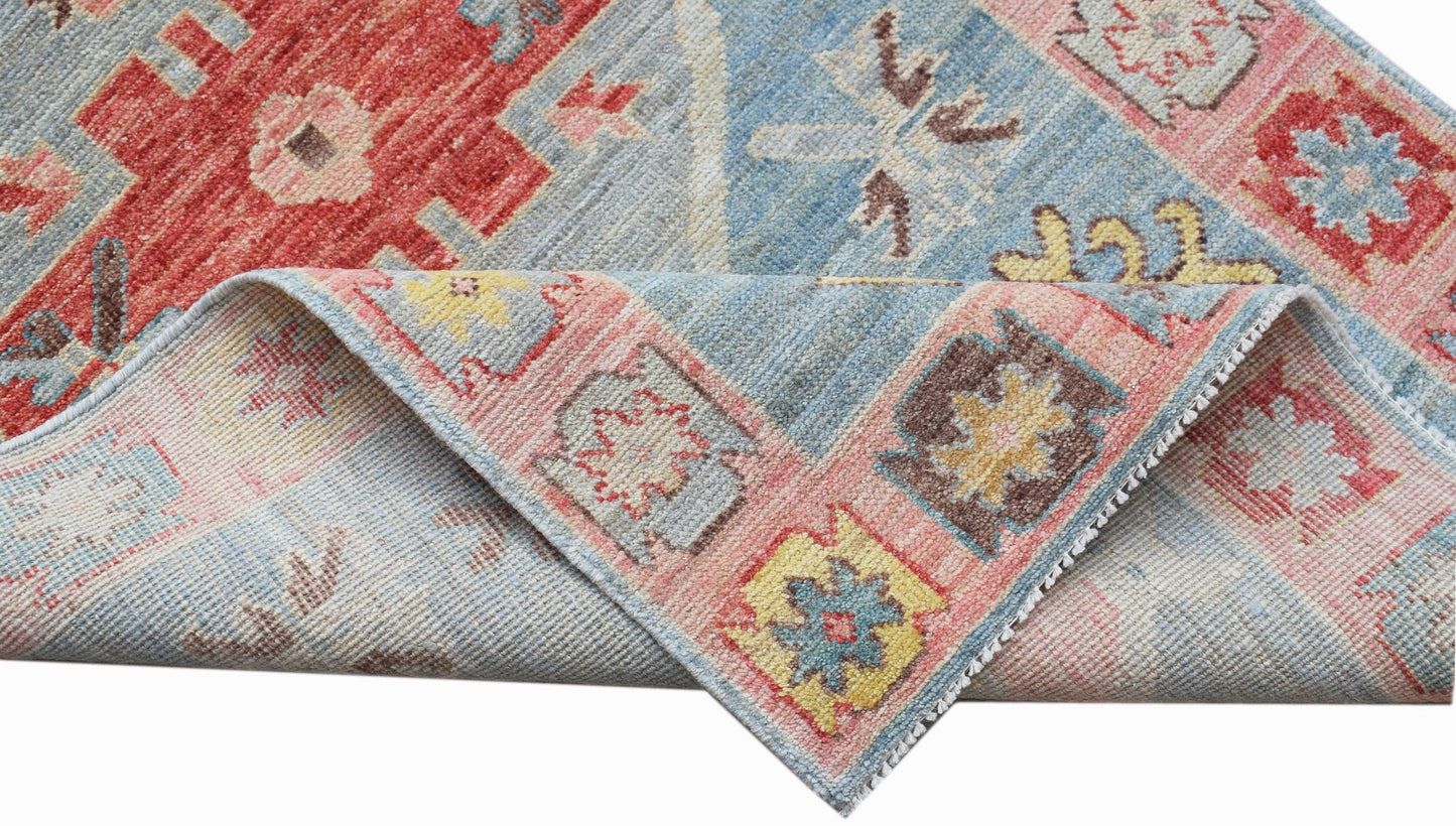 A handwoven transitional Oushak runner featuring a floral pattern in blue, red, and pink tones.