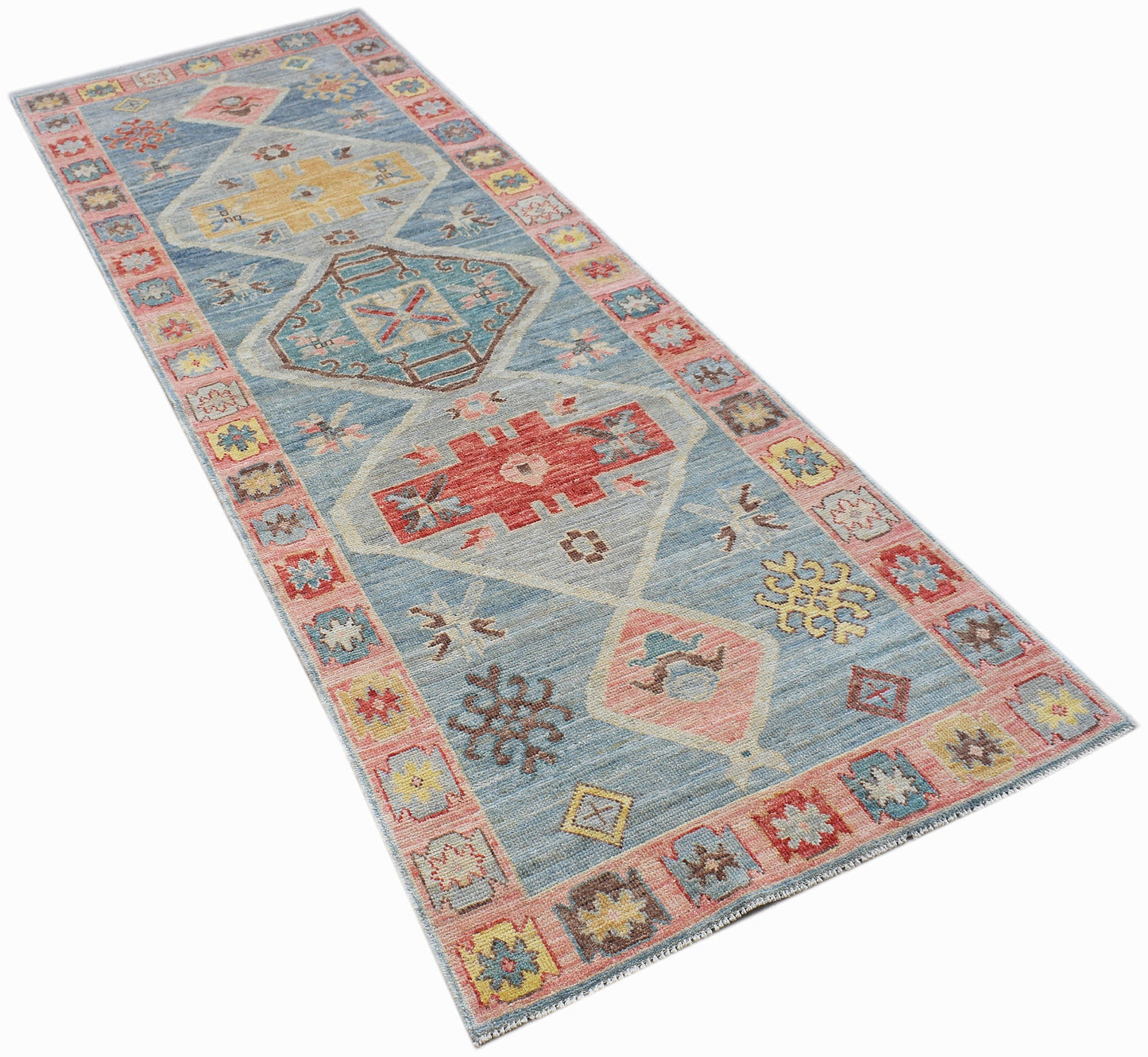 A handwoven transitional Oushak runner rug featuring geometric patterns in blue, red, and yellow.