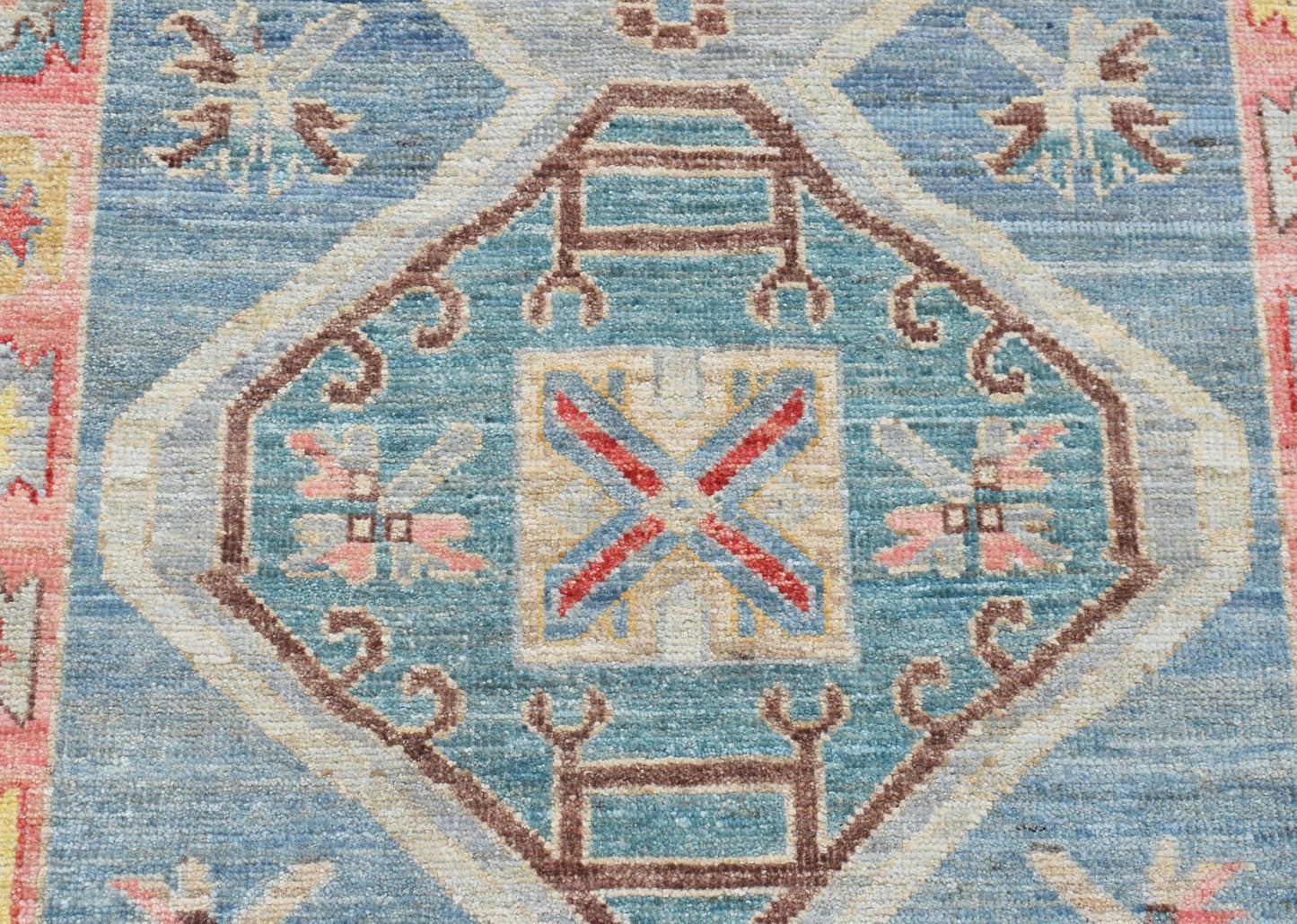 A handwoven transitional Oushak runner featuring a blue central medallion with geometric patterns.