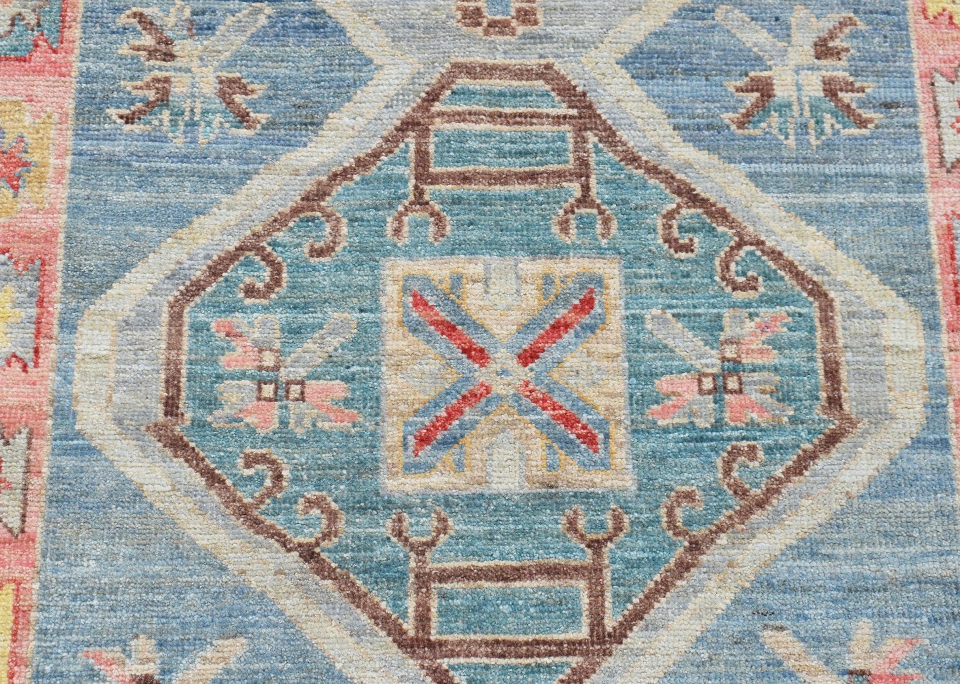 A handwoven transitional Oushak runner featuring a blue central medallion with geometric patterns.