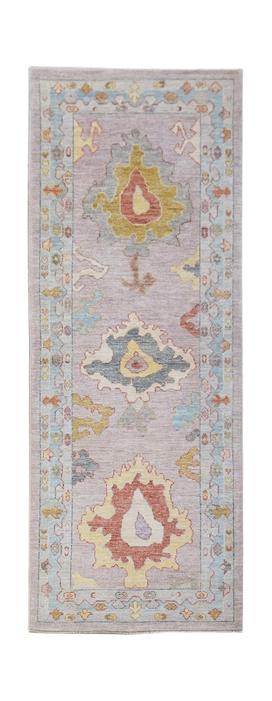 A handwoven wool runner rug featuring a transitional Oushak floral pattern in soft pastel tones.