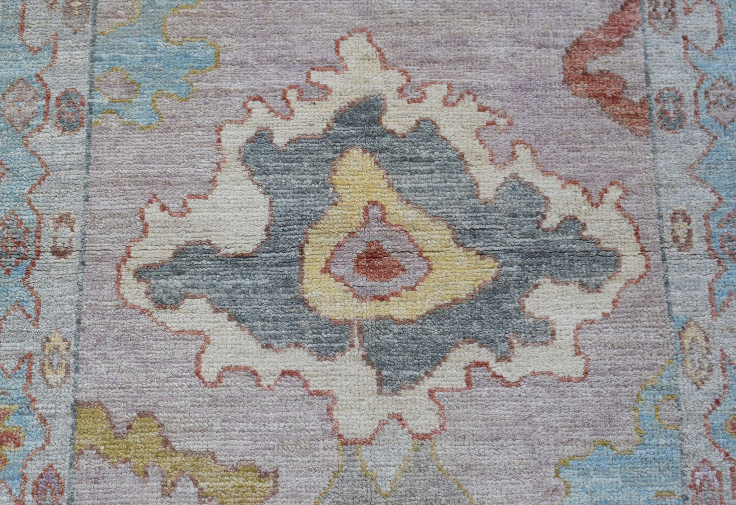 A handwoven wool runner featuring a transitional floral pattern in soft grey, yellow, and blue.