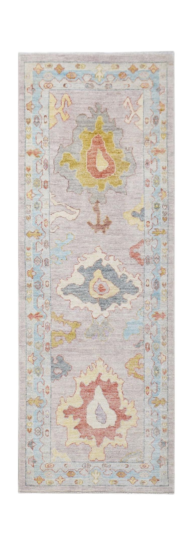 A handwoven wool runner rug featuring a transitional Oushak floral pattern in soft pastel tones.