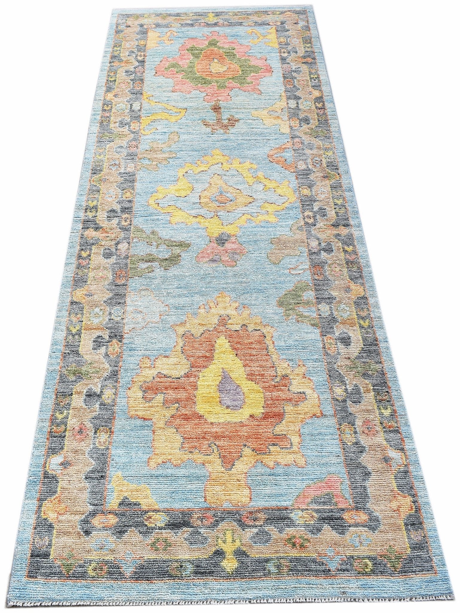 A handwoven wool runner rug featuring a light blue background with colorful floral motifs.