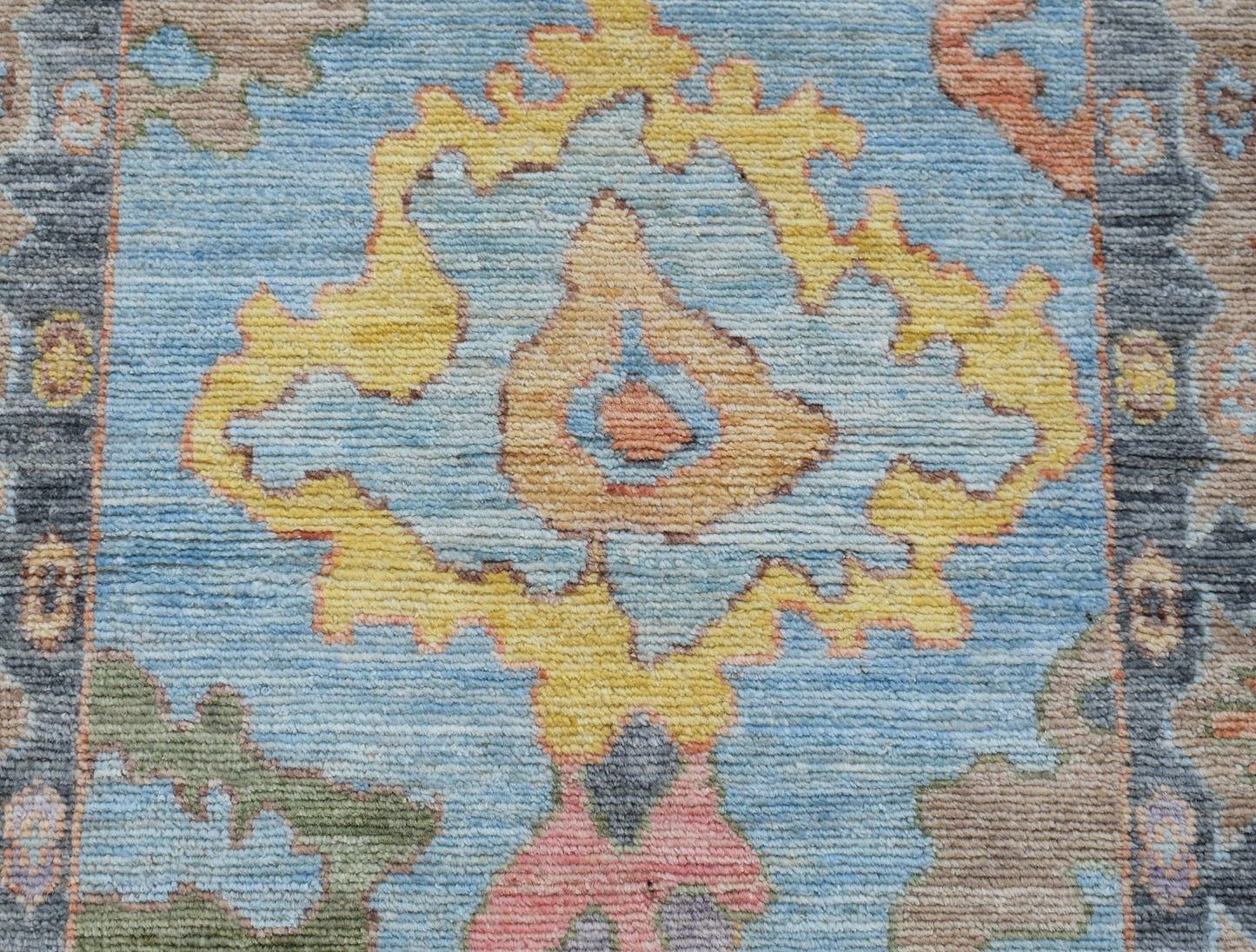 A handwoven transitional Oushak runner featuring a floral pattern in blue, yellow, and soft tones.