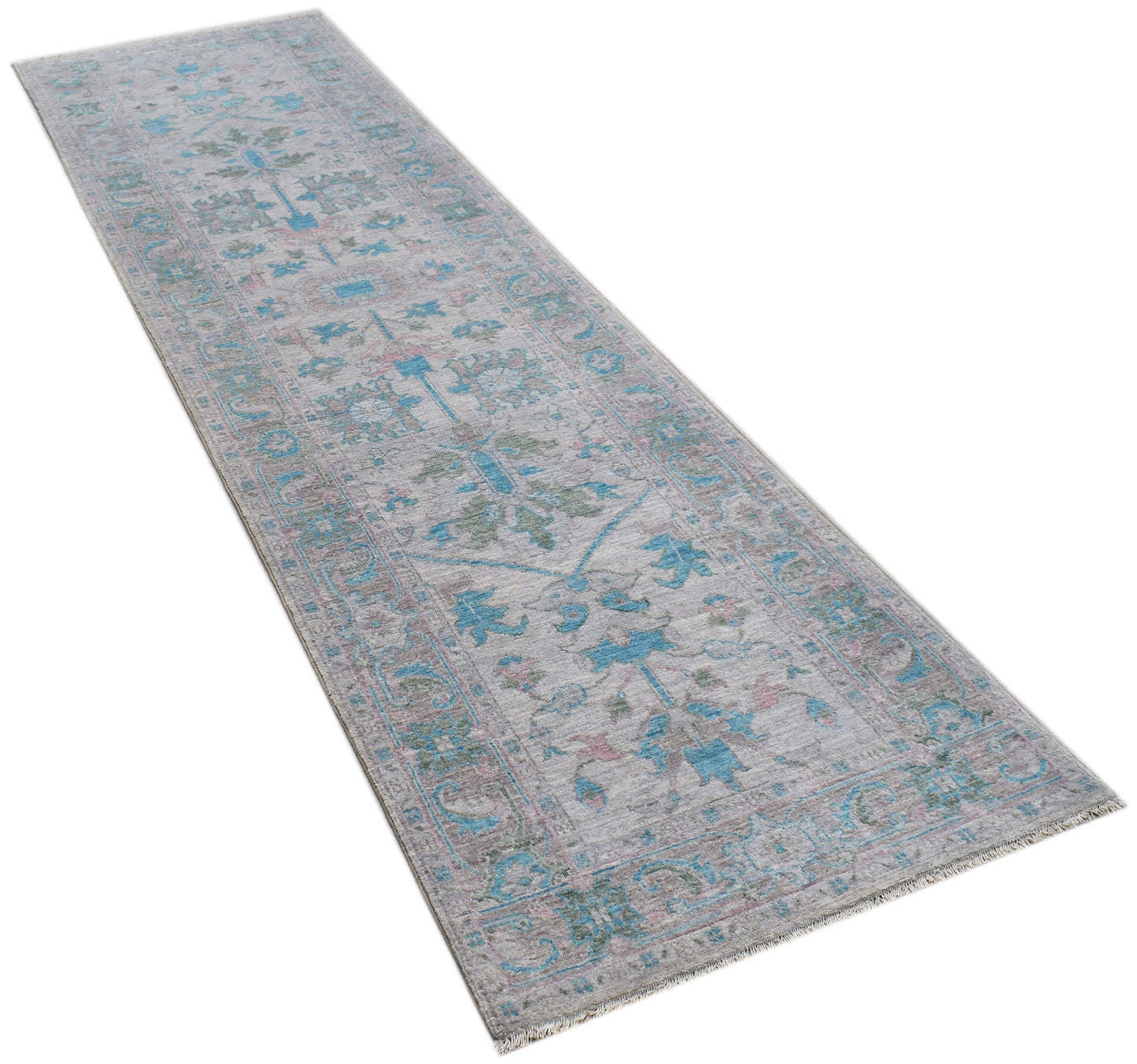 A handwoven wool runner rug featuring a transitional floral pattern in blue, green, and pink tones.