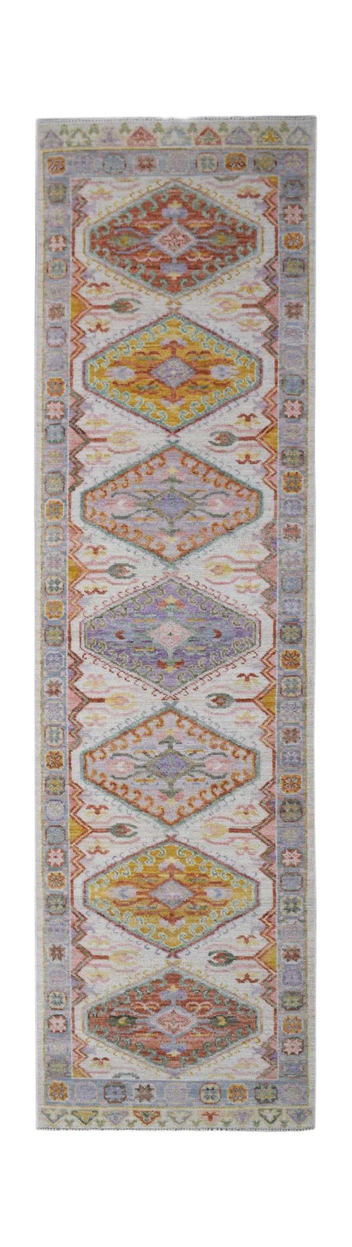 A handwoven wool runner rug featuring a repeating diamond pattern in soft, multicolored tones.
