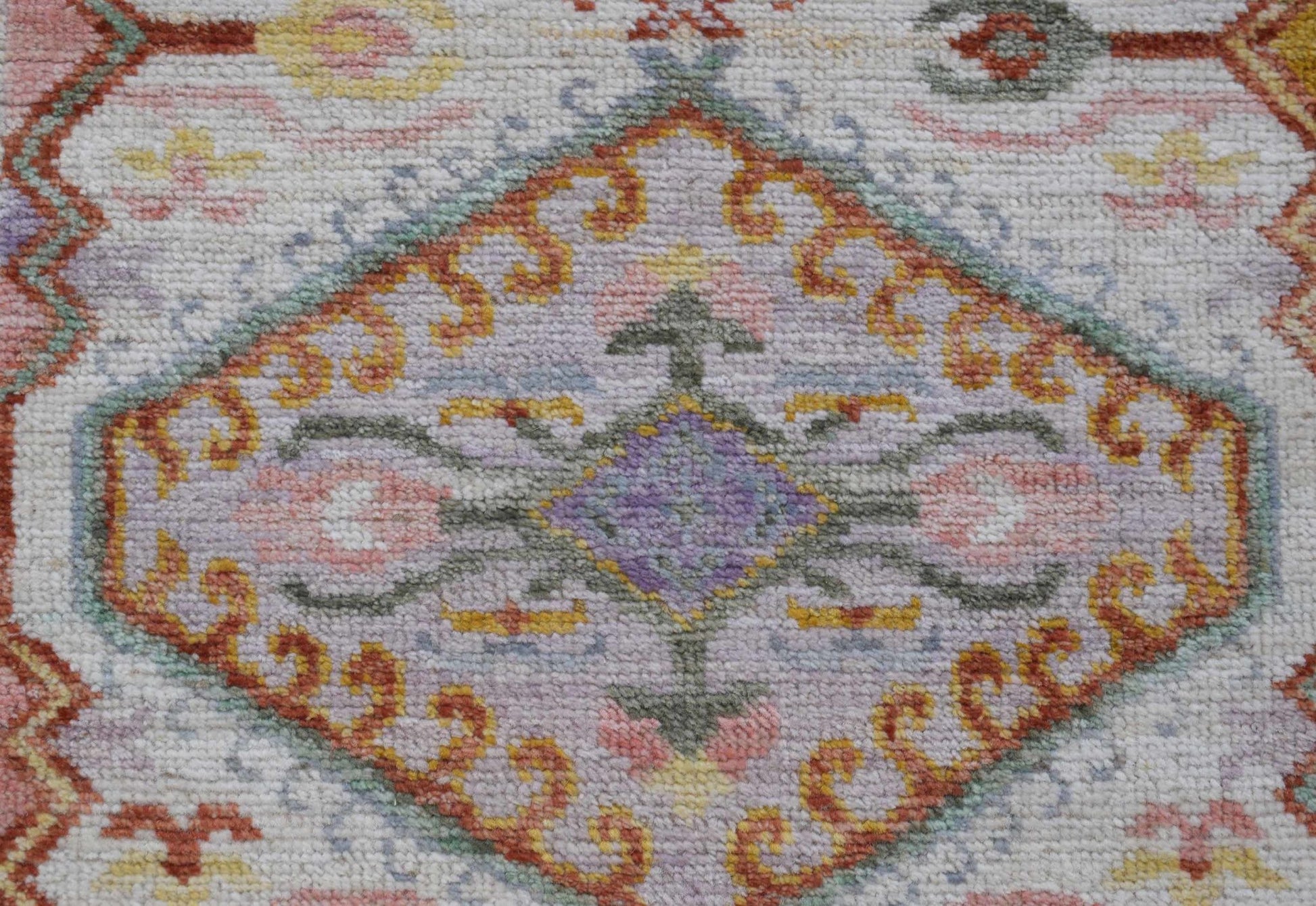 A handwoven Oushak runner featuring a central floral medallion in soft pastel tones.