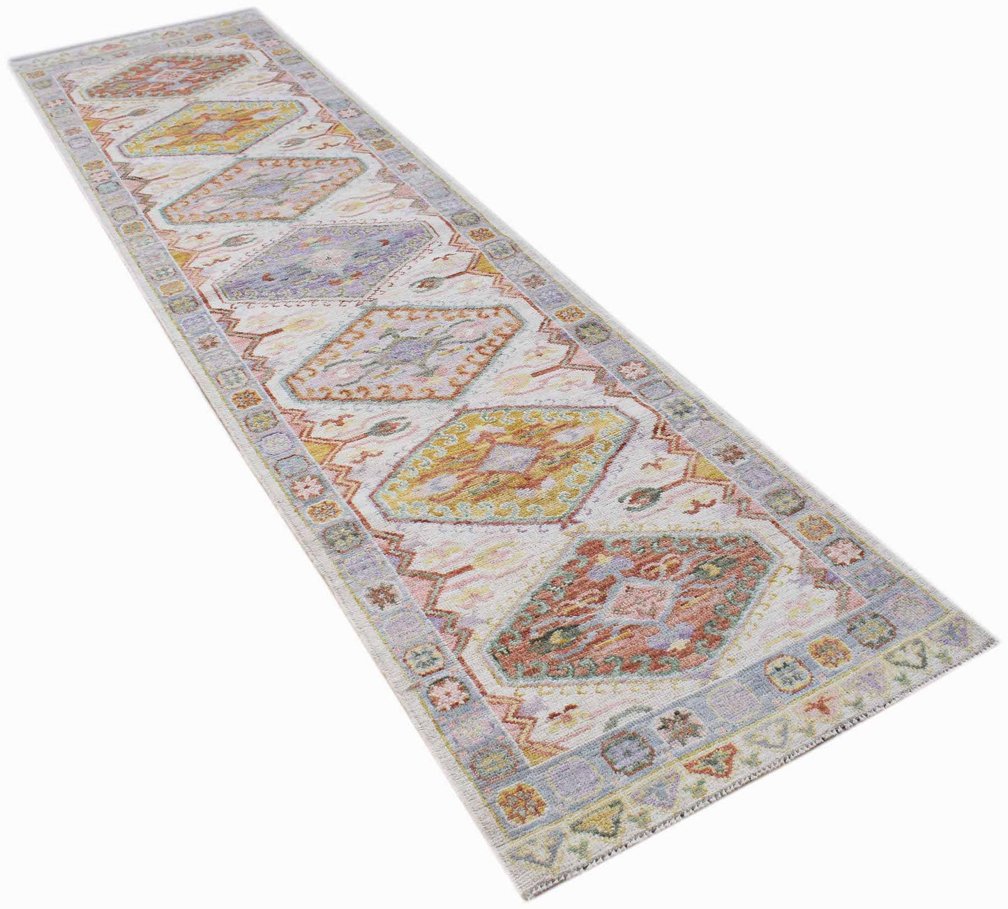 A handwoven wool runner rug featuring a transitional Oushak pattern in soft, multi-colored tones.
