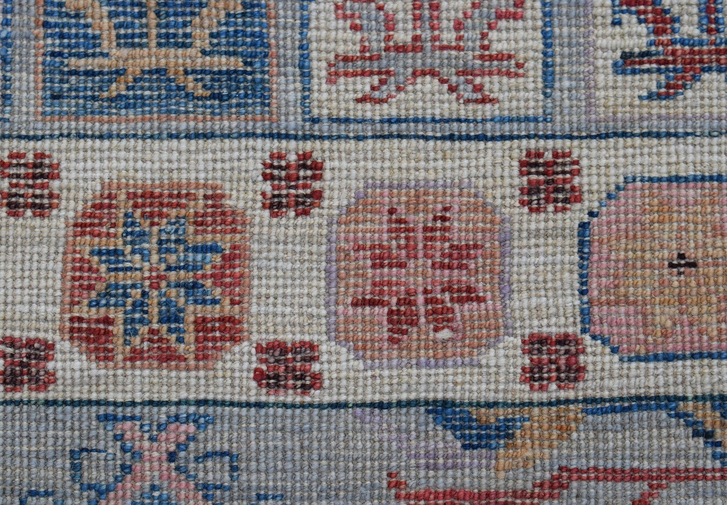 A handwoven wool runner featuring a geometric pattern of colorful squares on a cream background.