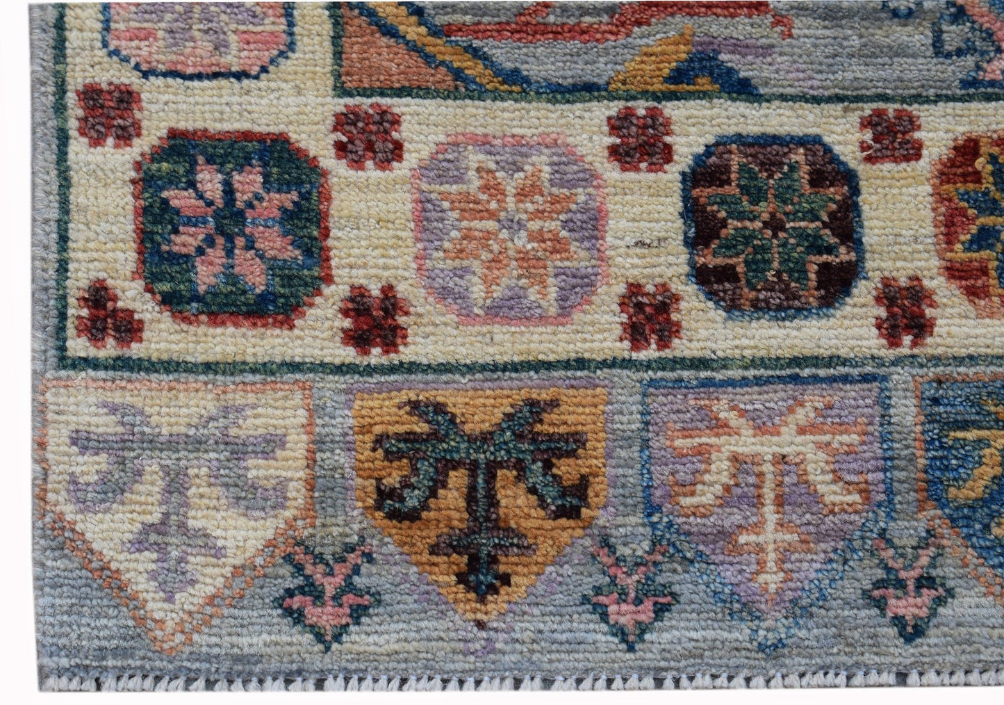 A handwoven wool runner featuring a geometric pattern of floral motifs in muted, earthy tones.