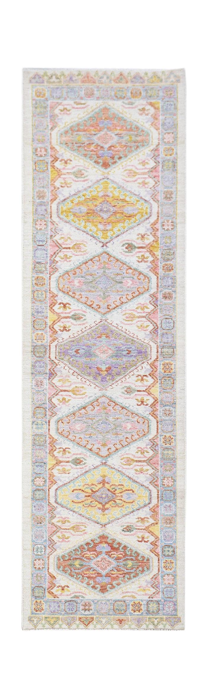A handwoven wool runner rug featuring a transitional Oushak pattern in soft pastel colors.