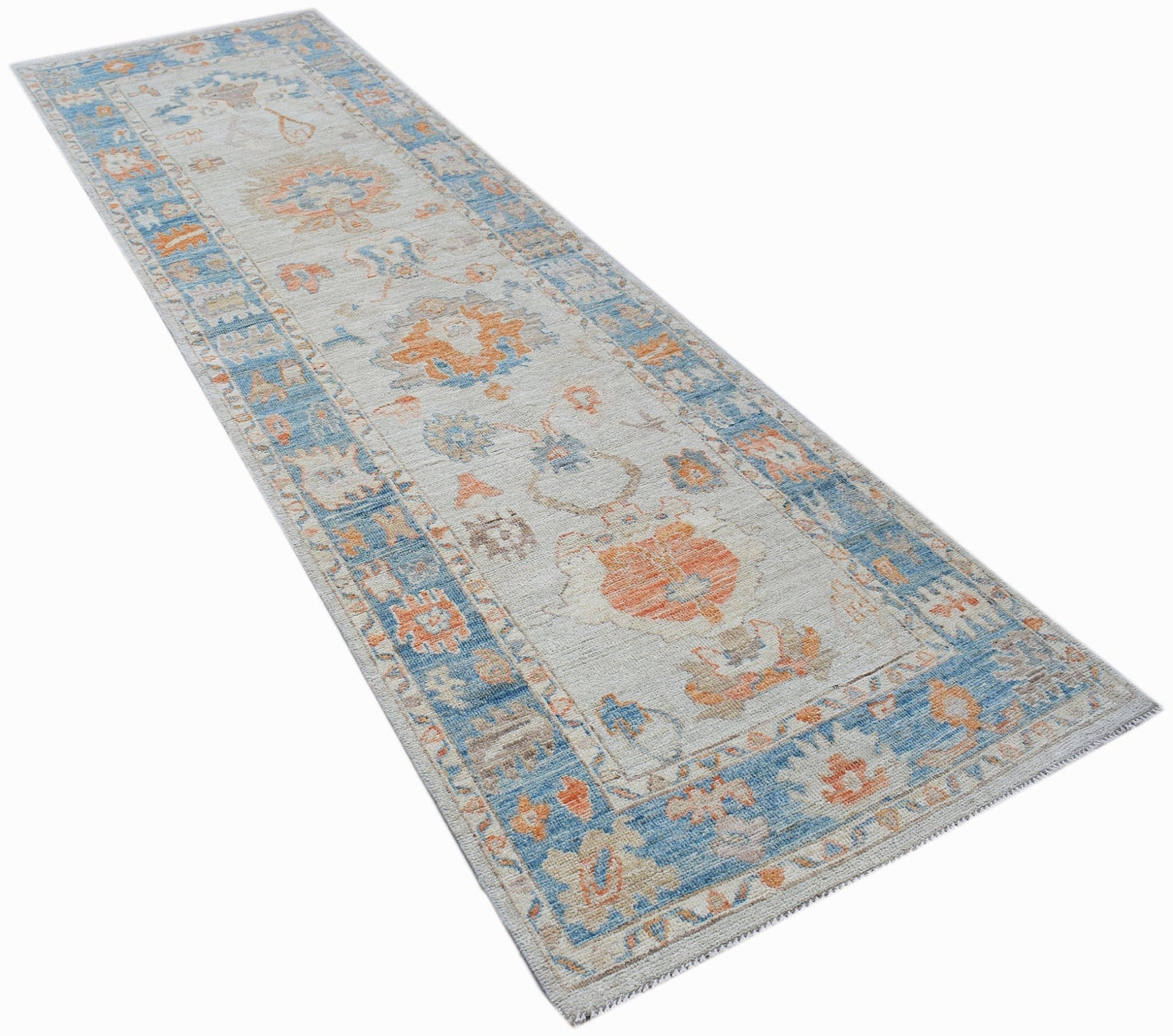 A handwoven wool runner rug featuring a transitional floral pattern in blue and orange tones.