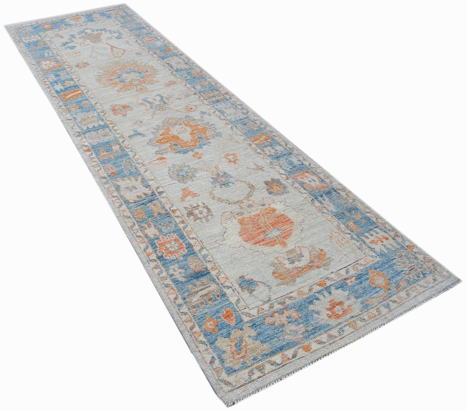 A handwoven wool runner rug featuring a transitional floral pattern in blue and orange tones.