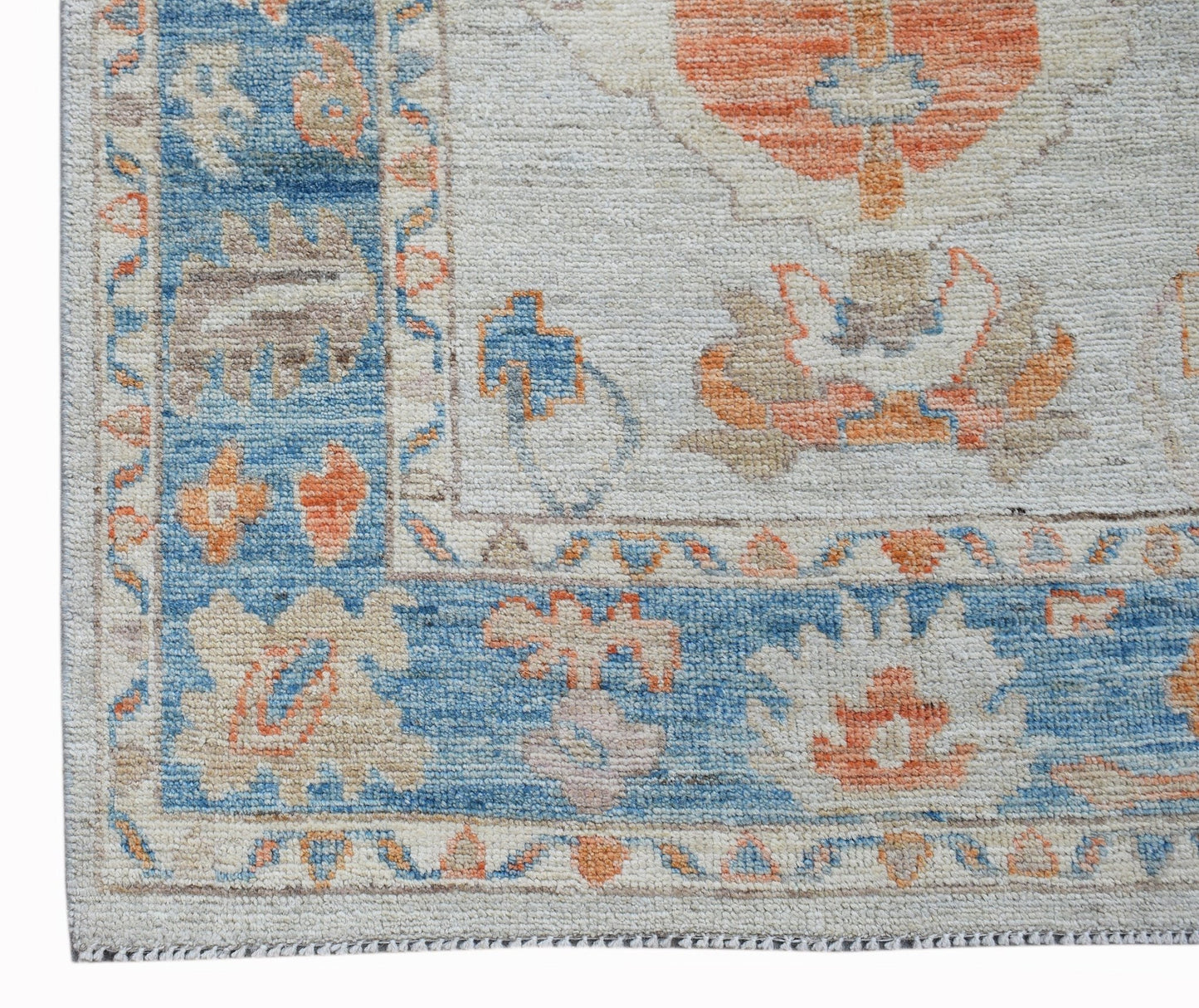 A handwoven wool runner featuring a transitional floral pattern in blue, orange, and cream tones.