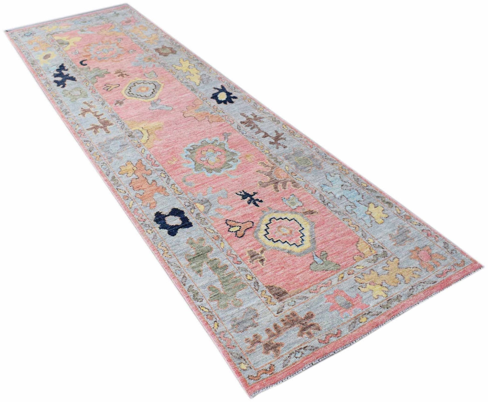 A handwoven transitional Oushak runner featuring a floral pattern in pink, blue, and yellow tones.